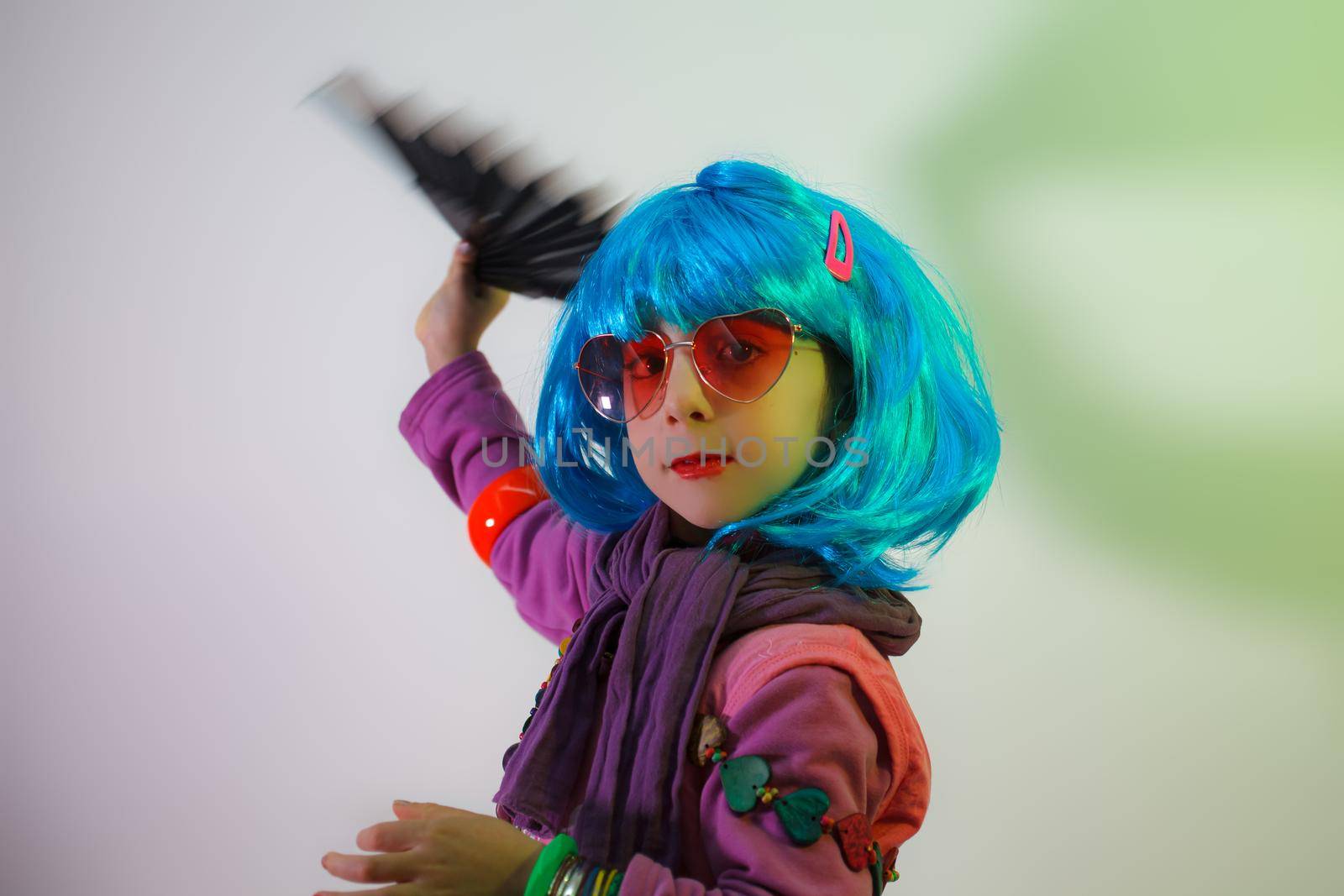Child with blue wig posing with a fan for a photo shoot