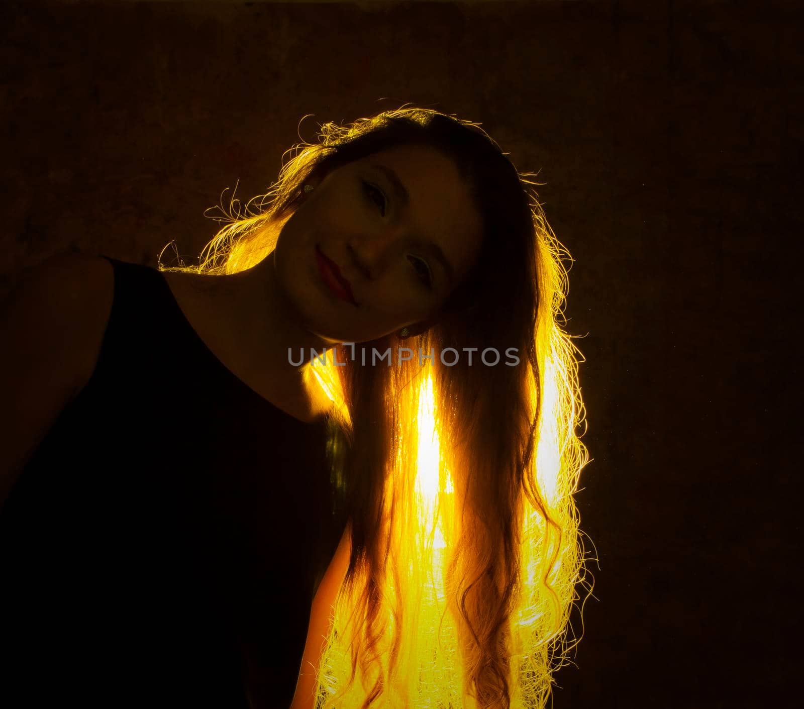 Portrait against the gold light of a young beautiful woman