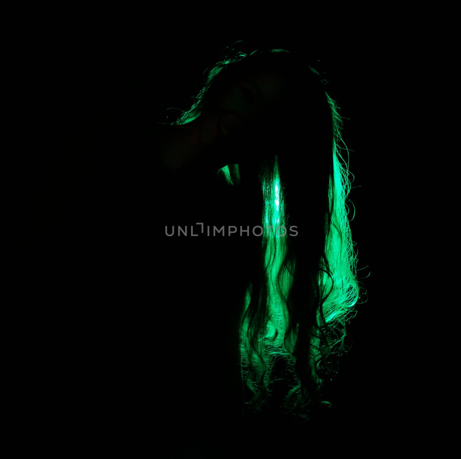 Portrait against the green light of a young beautiful woman