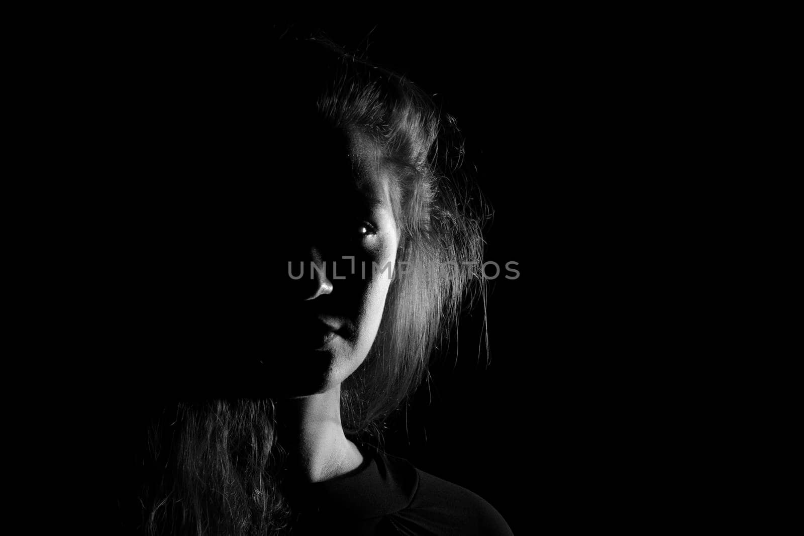 Black and white portrait of a joung woman on black background by bepsimage