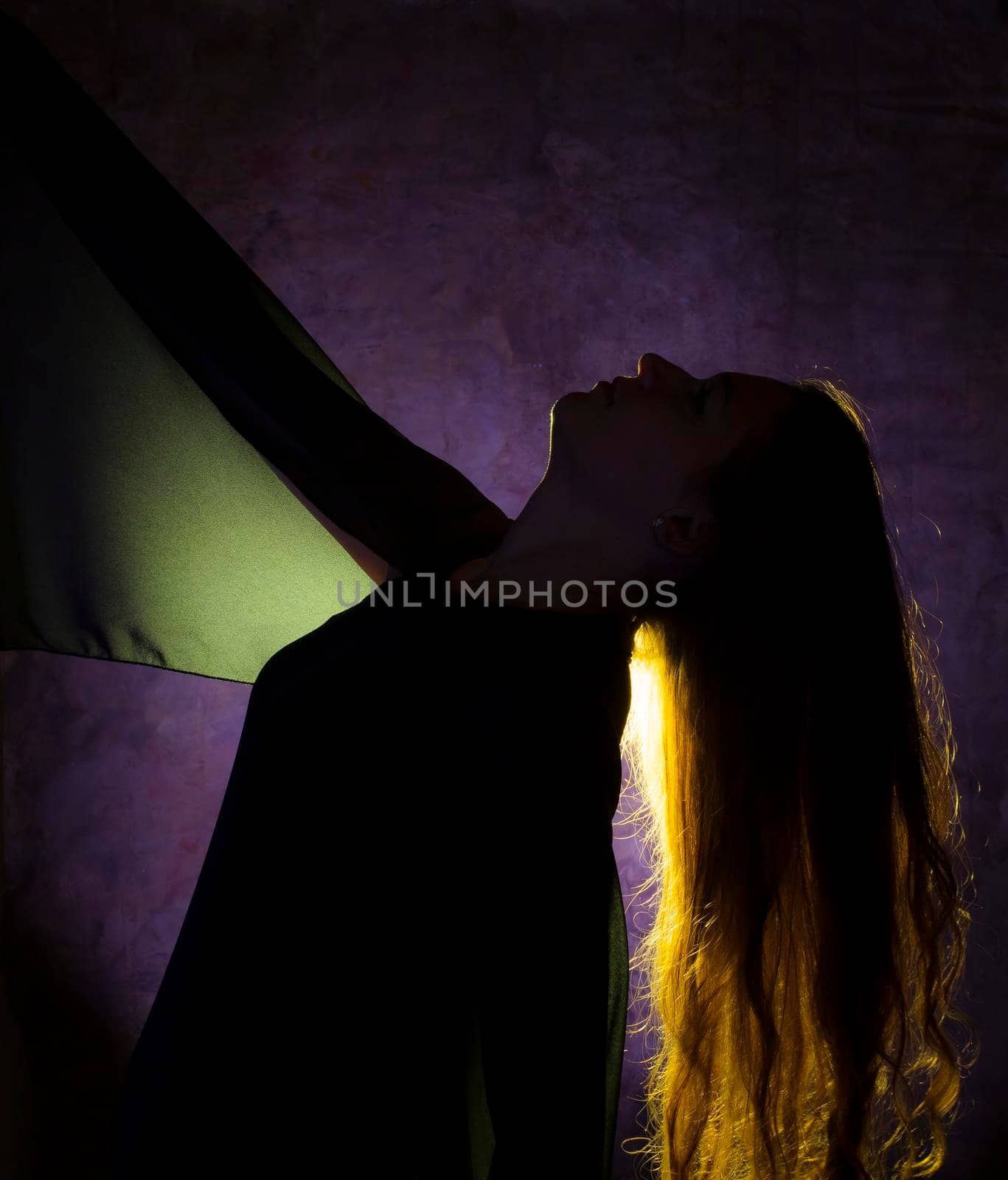 Portrait against the gold light of a young beautiful woman posing on blue background