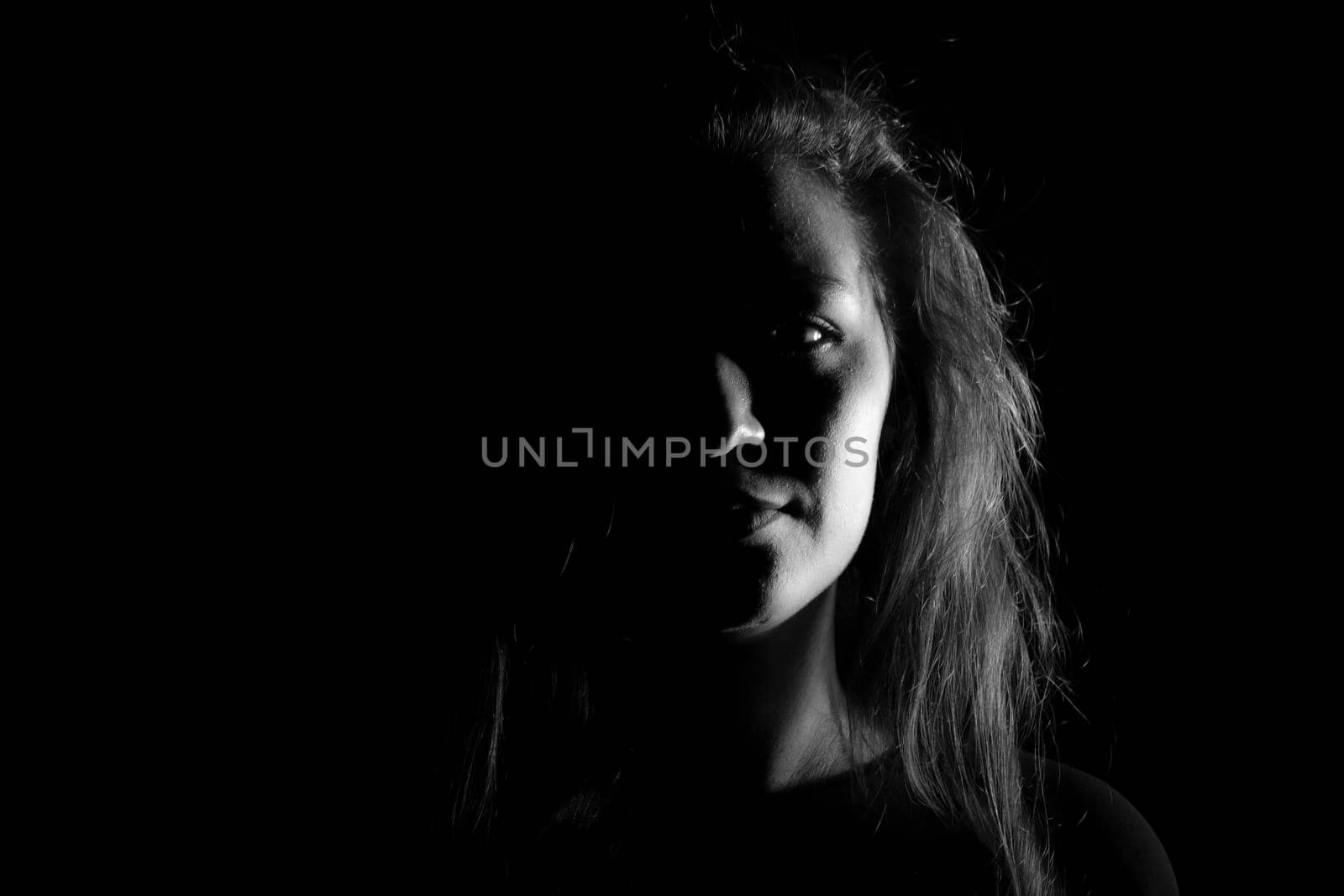 Black and white portrait of a joung woman on black background by bepsimage