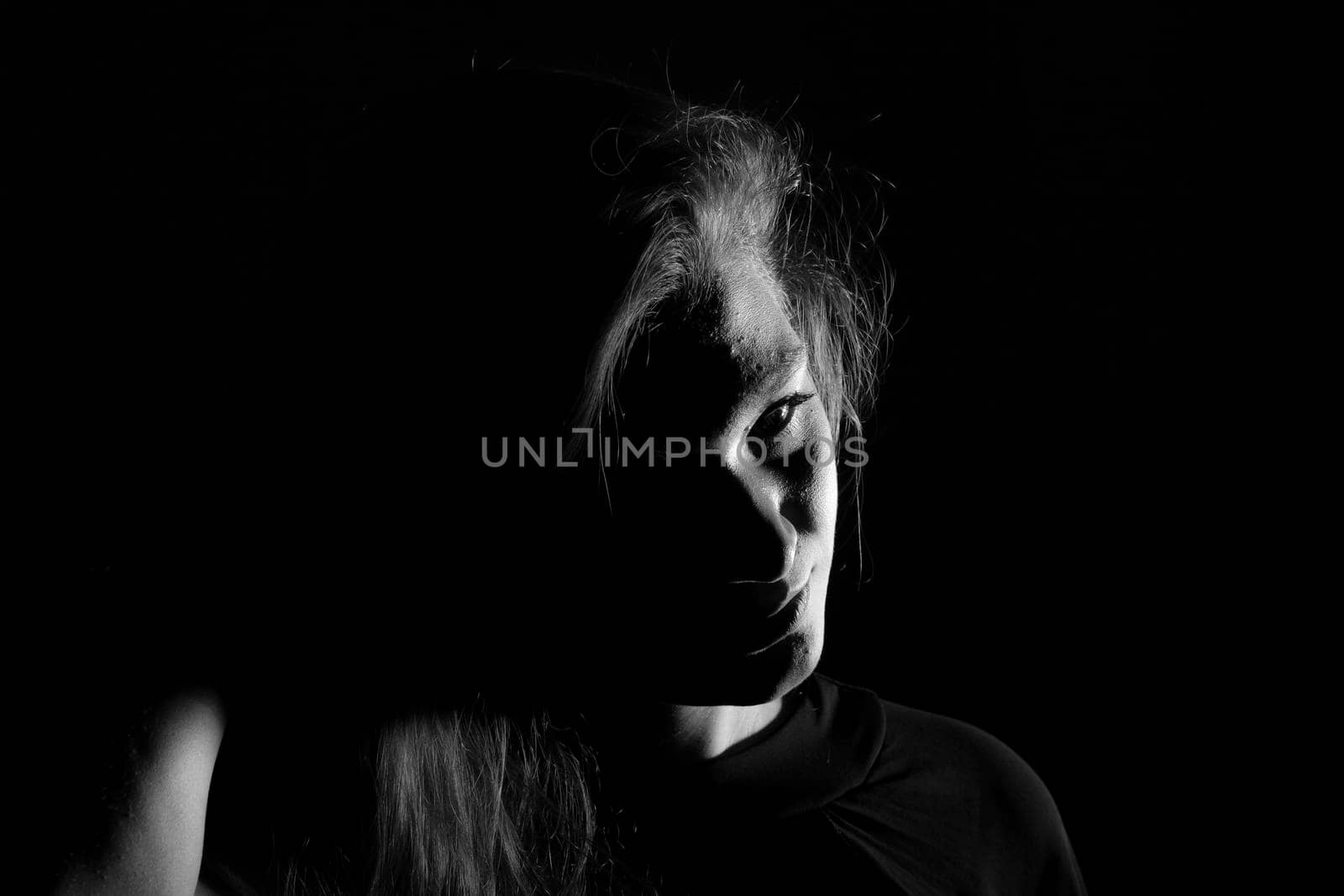 Black and white portrait of a joung woman on black background by bepsimage