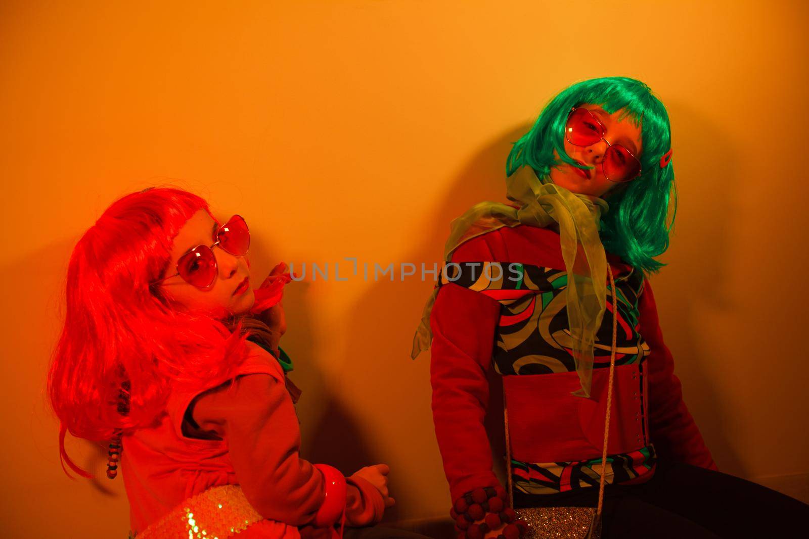 Little girls wearing a colorful wig and heart-shaped sunglasses posed for a photo shooting on the disco light background