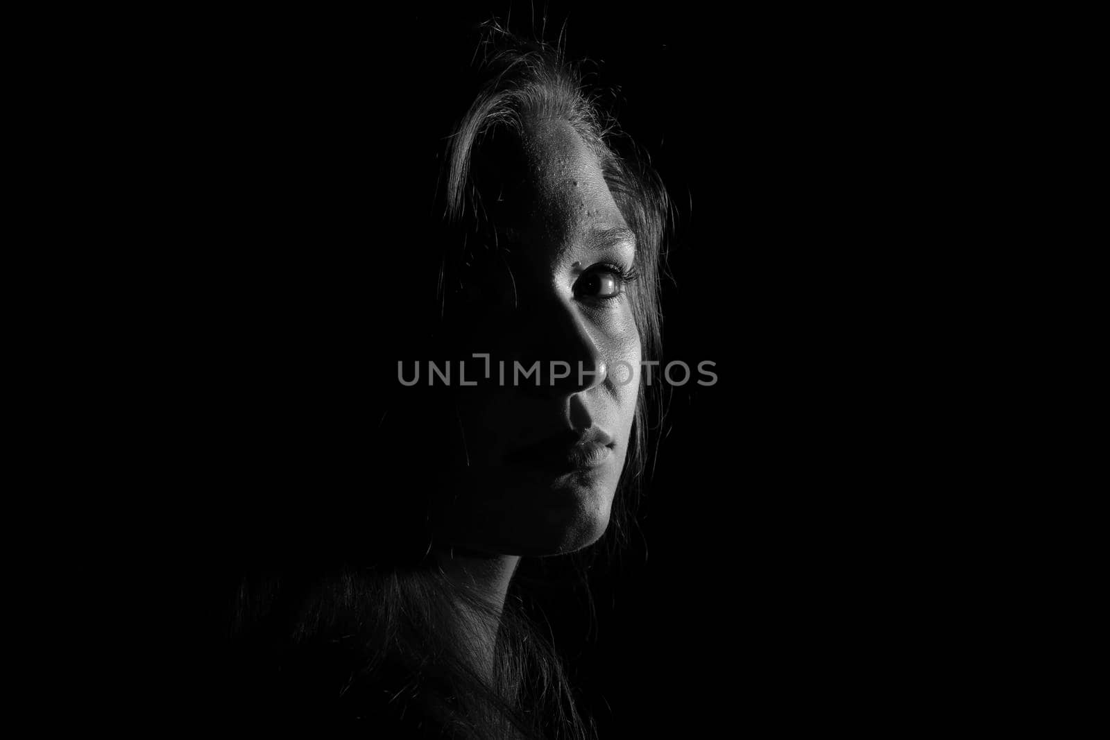 Black and white portrait of a joung woman on black background by bepsimage