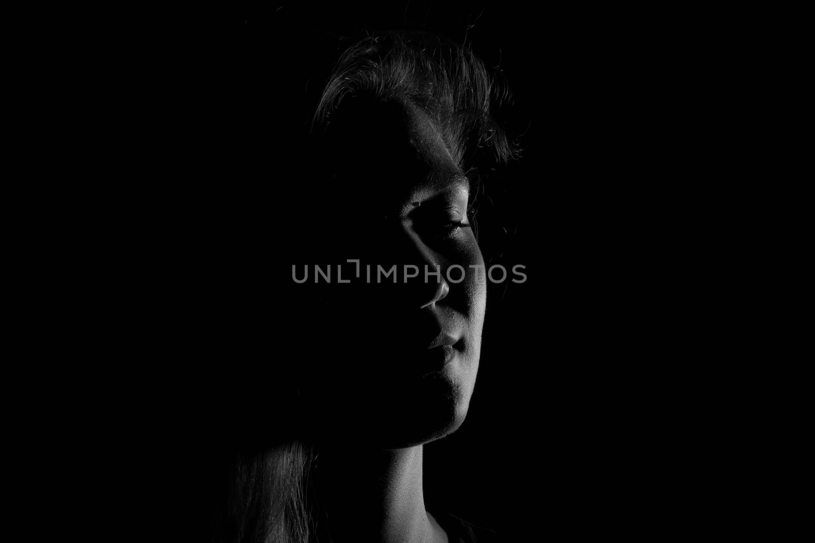 Black and white portrait of a joung woman on black background by bepsimage