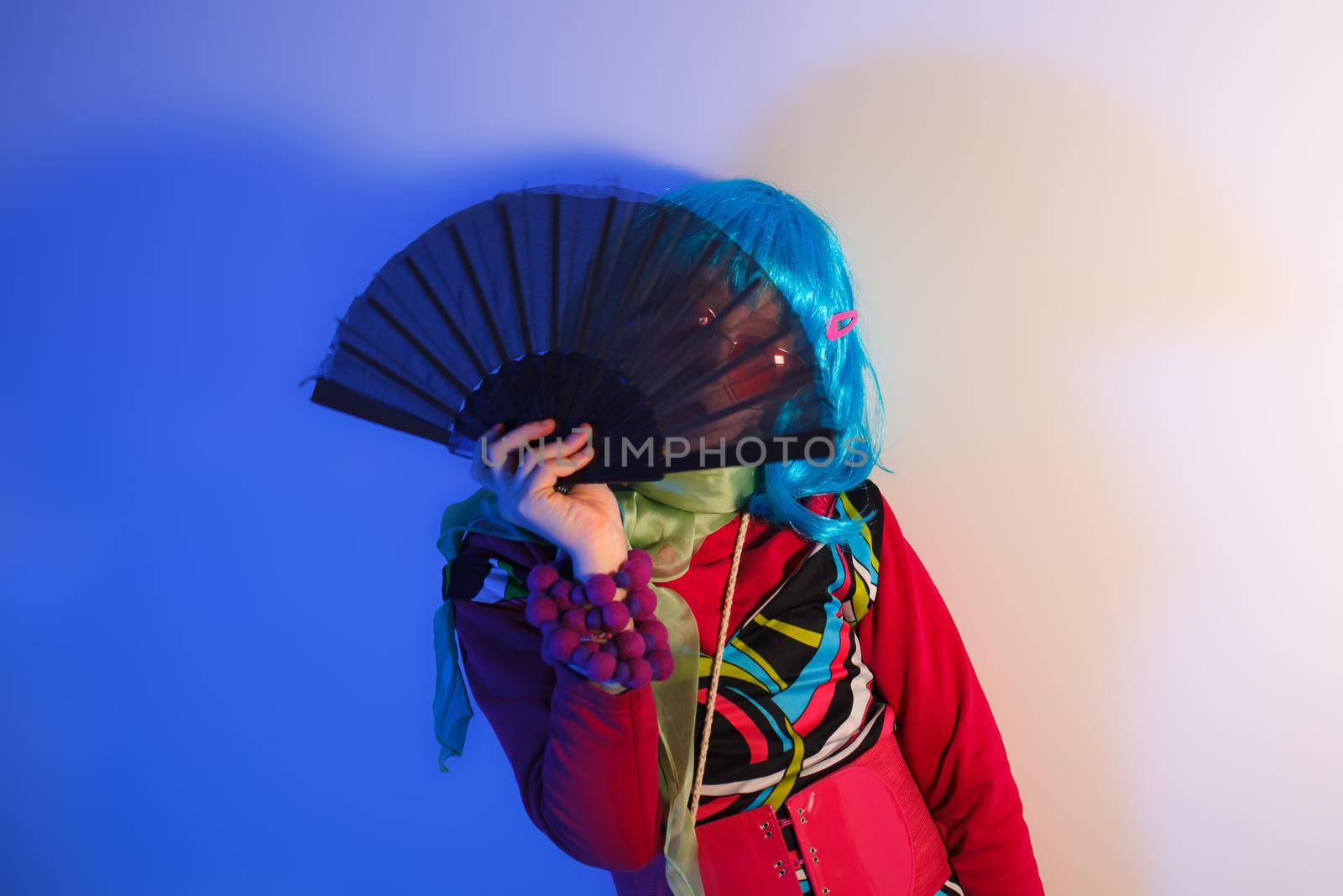 Little girl posing with a fan for a photo shoot on a colorful background