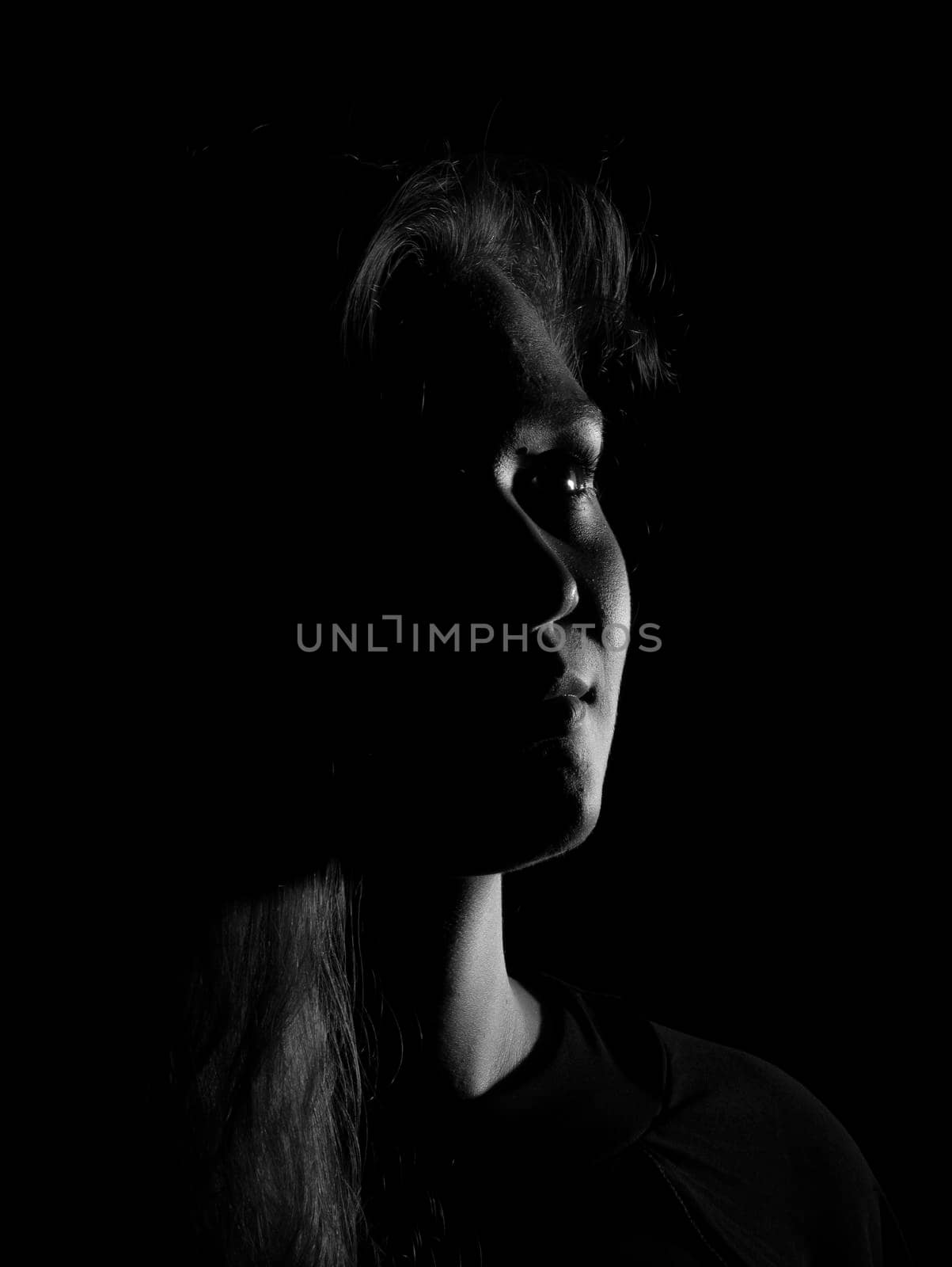 Black and white portrait of a joung woman on black background by bepsimage