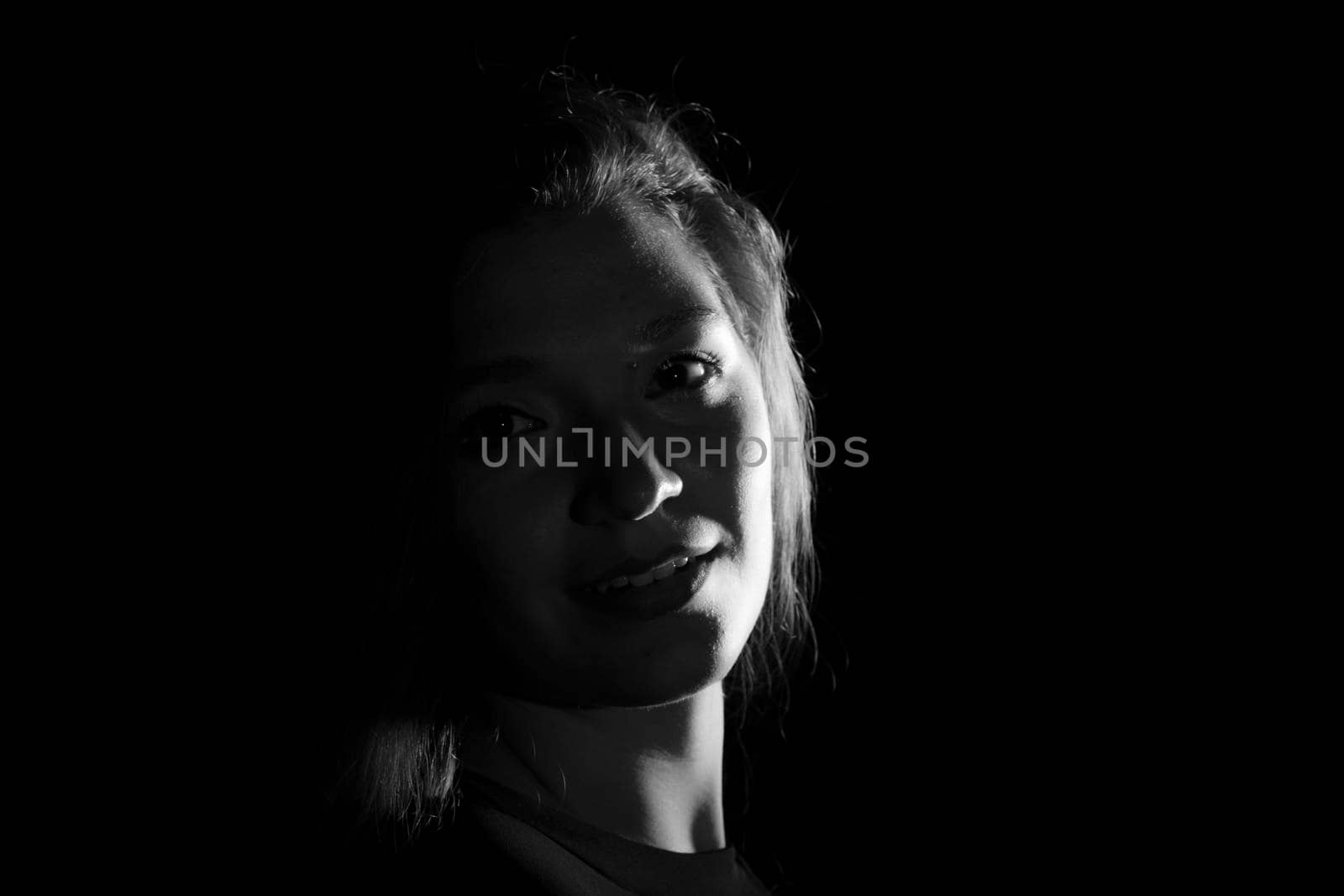 Black and white portrait of a joung woman on black background by bepsimage