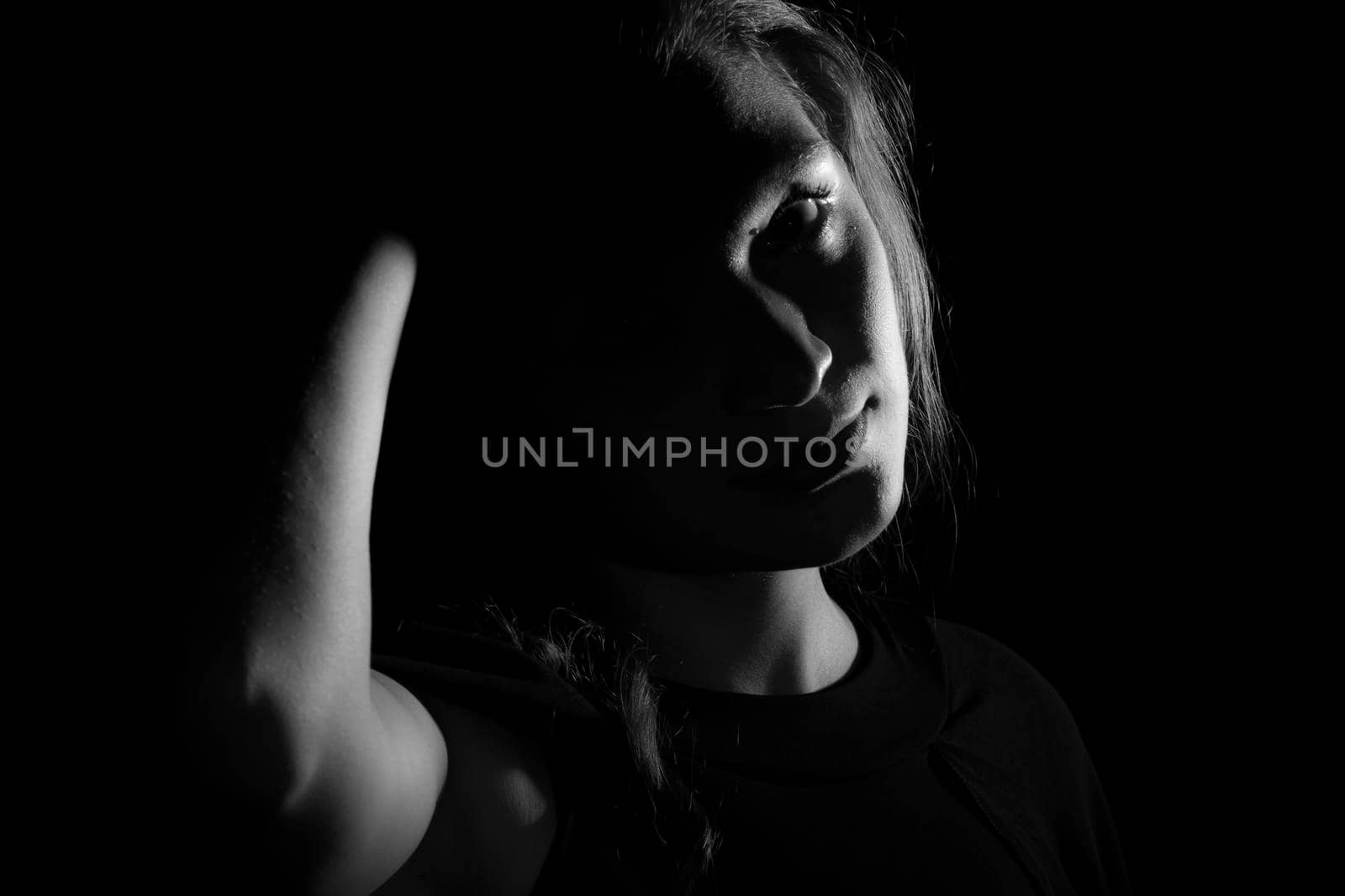 Black and white portrait of a joung woman on black background by bepsimage