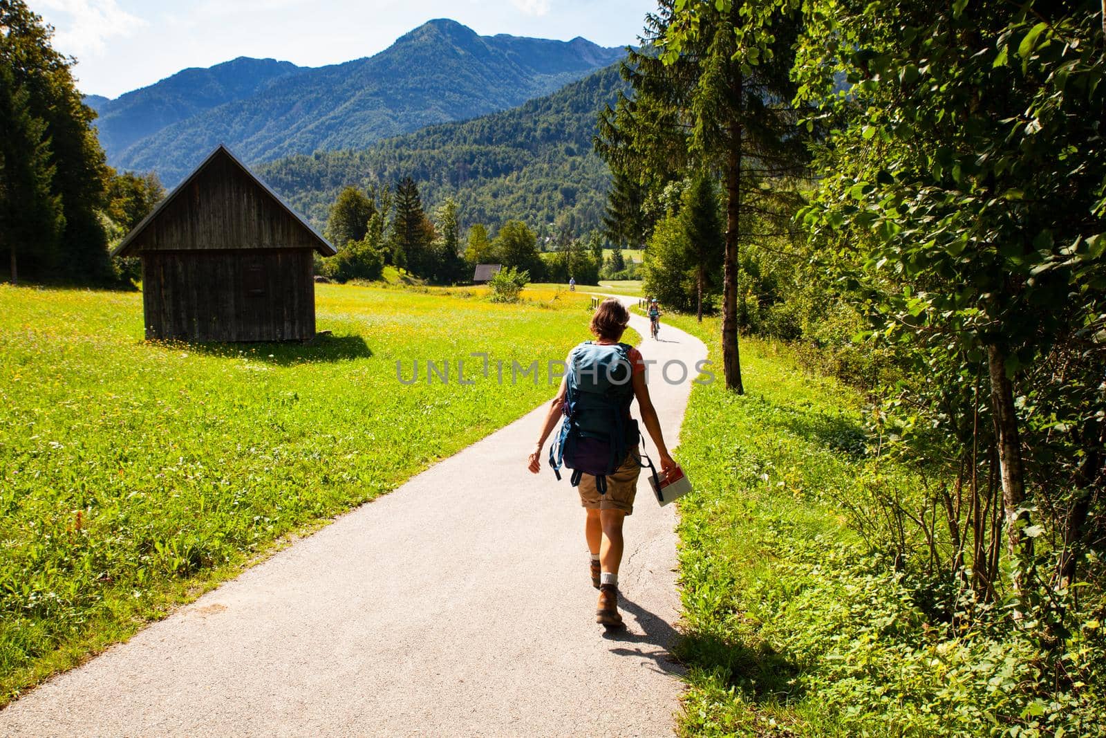 Young woman with backpack hiking along the path in the Slovenian countryside. Bohinj