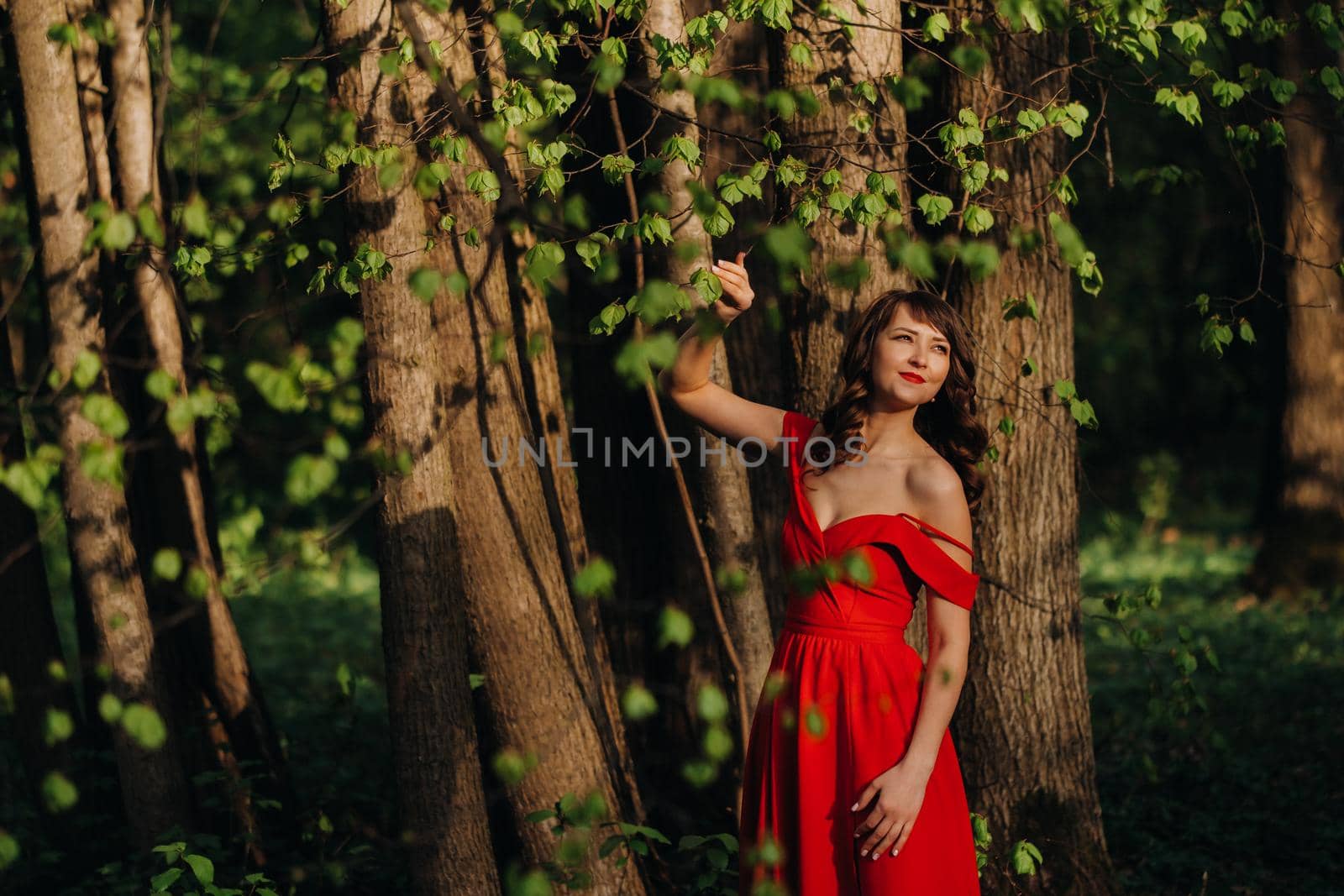 Spring Portrait of a laughing girl in a long red dress with long hair walking in the Park in the woods