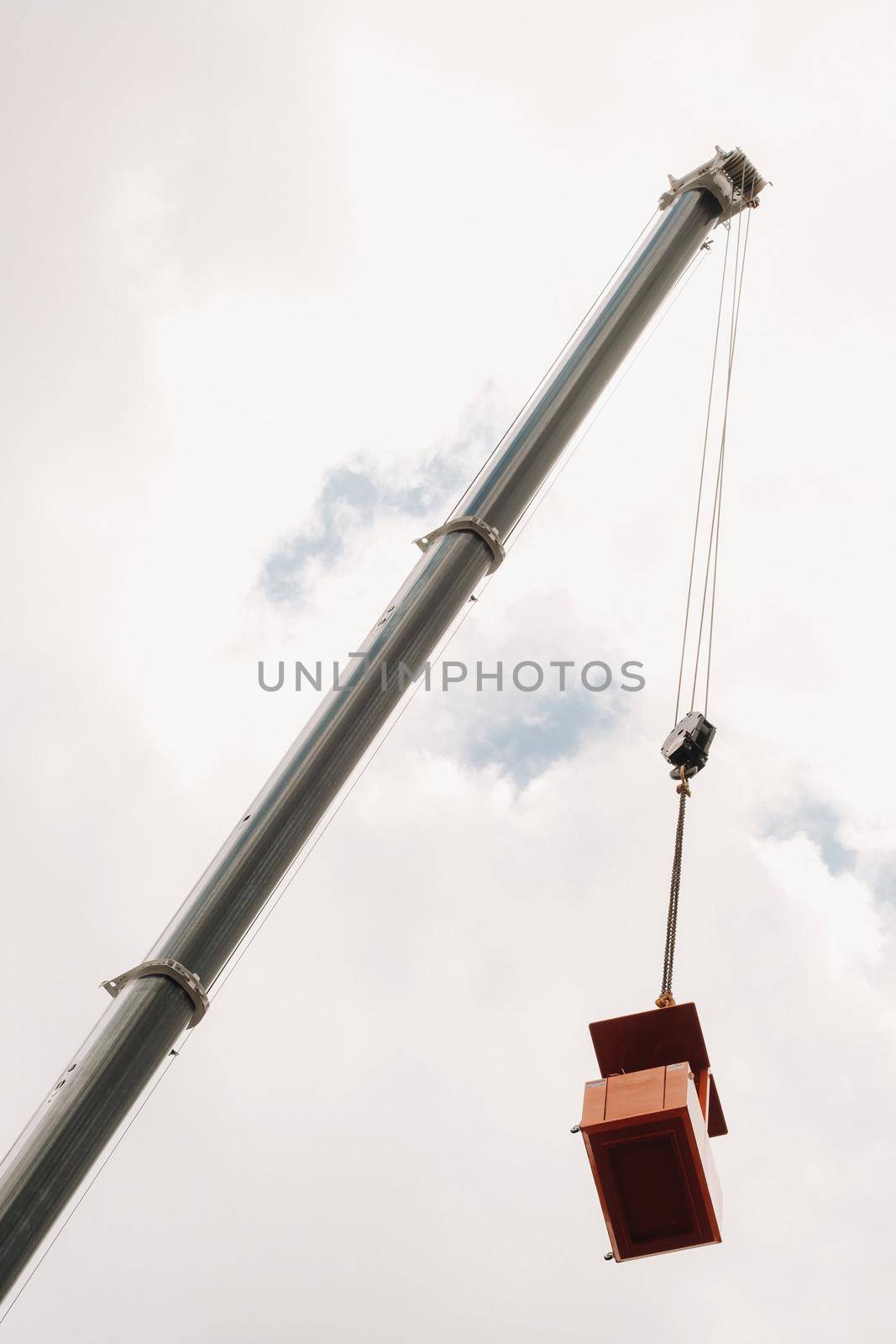 Raised high in the sky cradle of a car crane. The tallest truck crane with a yellow cradle for solving complex tasks by Lobachad