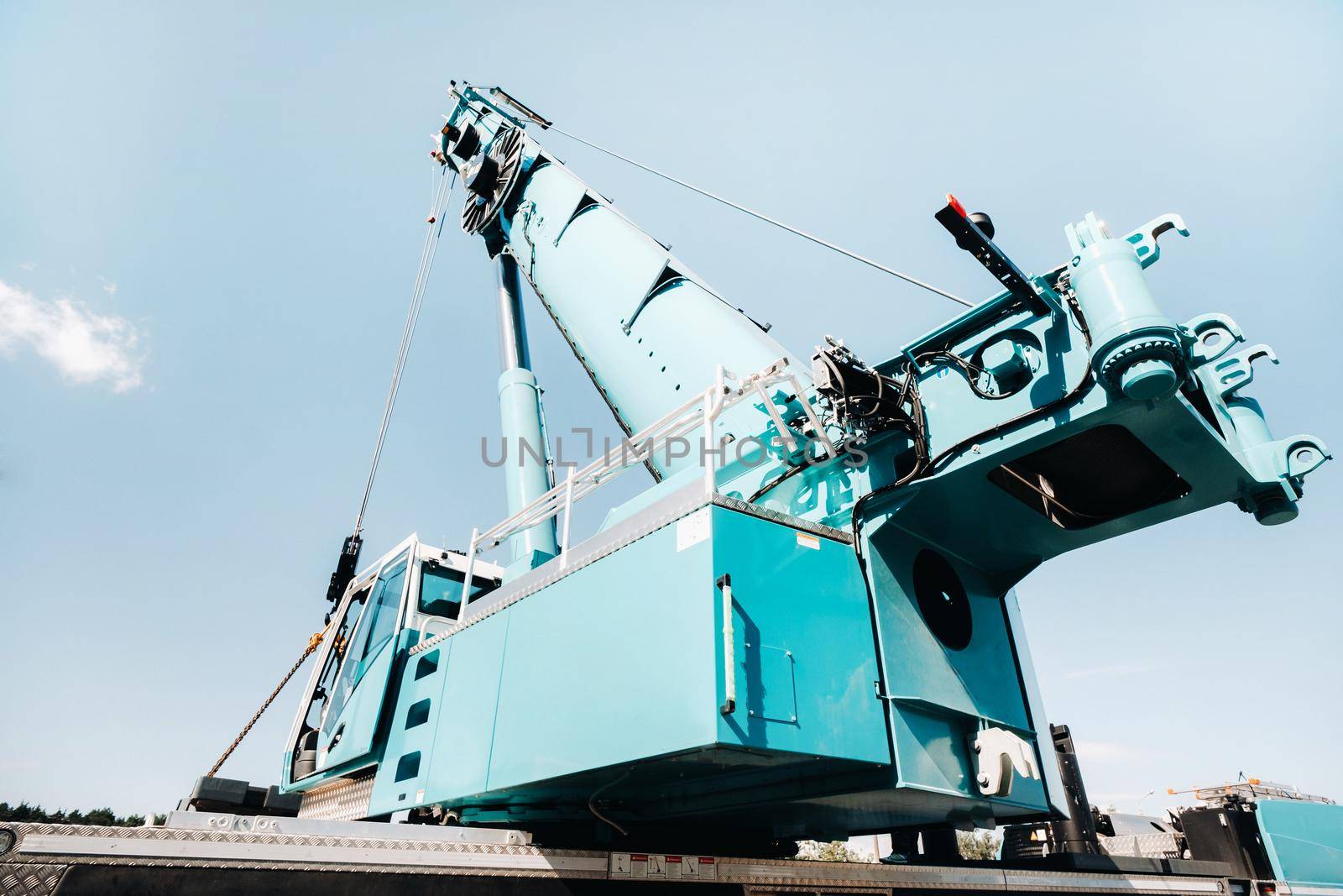 a cab with the operator of a Large blue car crane that stands ready to operate on hydraulic supports on a platform next to a large modern building. The largest truck crane for solving complex tasks