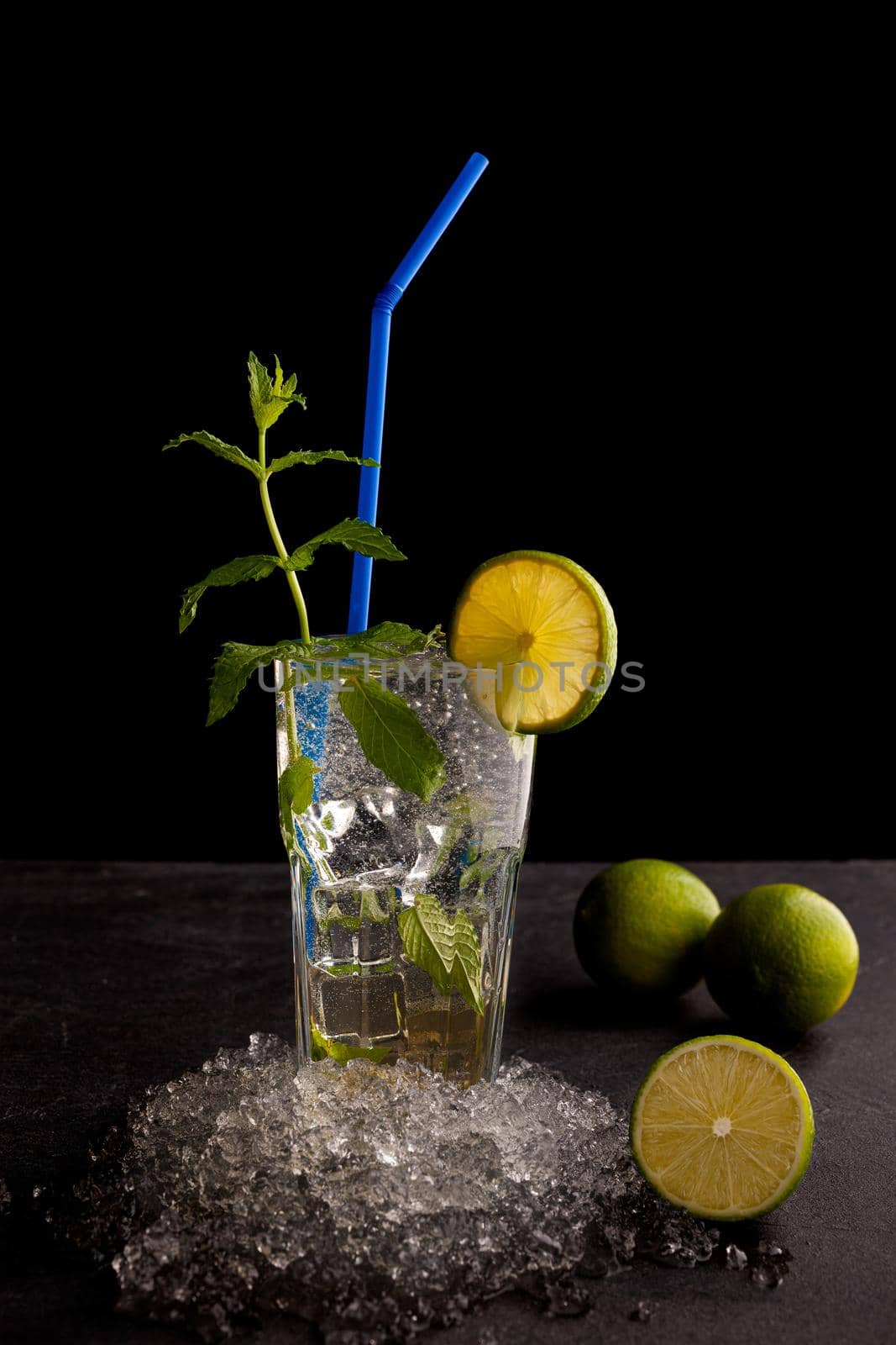 Delicious refreshing mint cocktail called mojito with rum and lime, cold drink or beverage with ice on black background