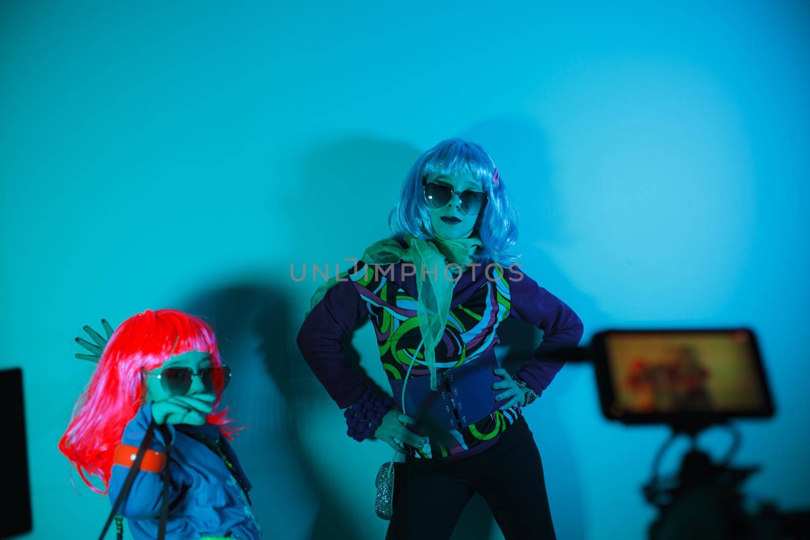 Little girls wearing a colorful wig and heart-shaped sunglasses posed for a photo shooting on the disco light background