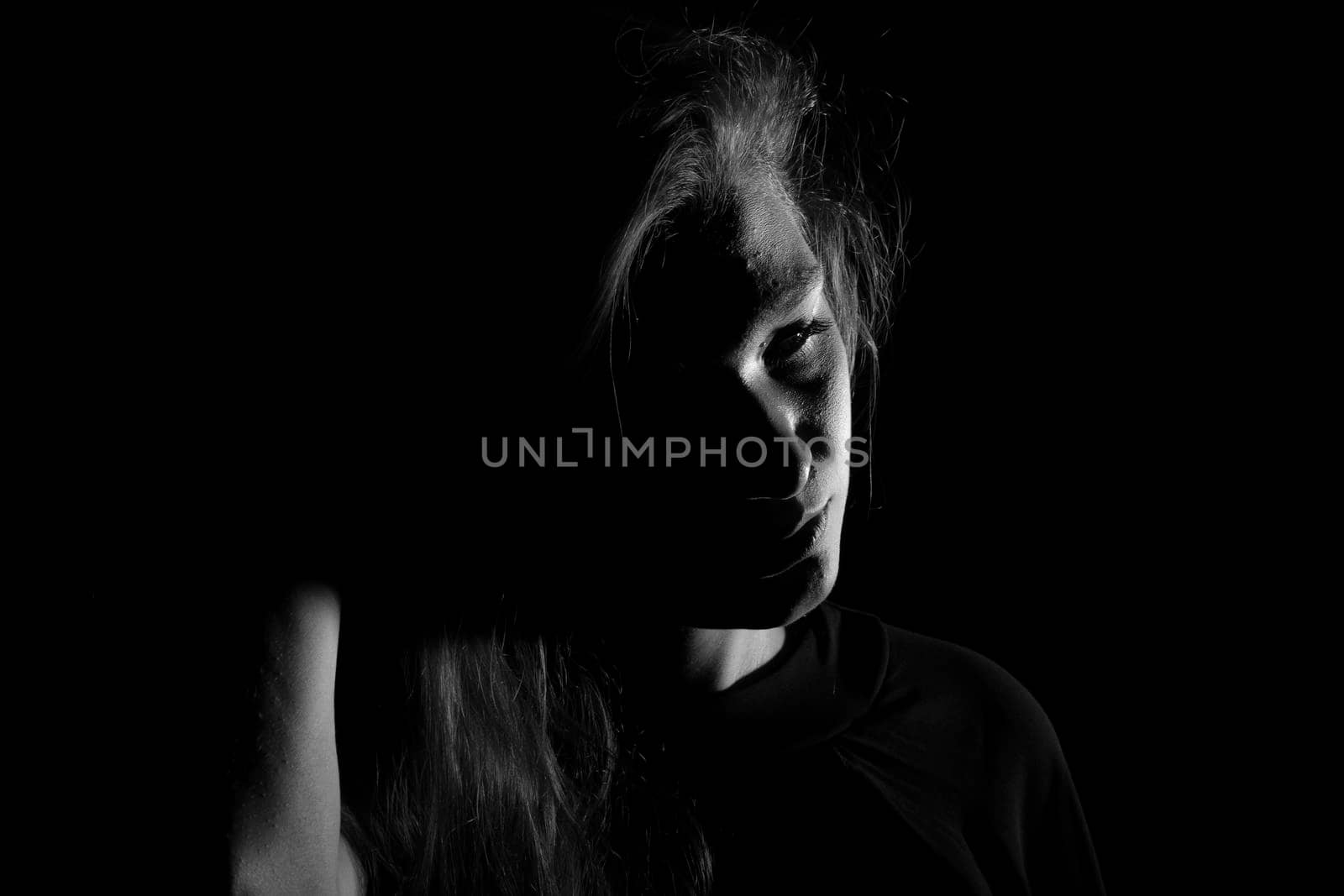 Black and white portrait of a joung woman on black background by bepsimage