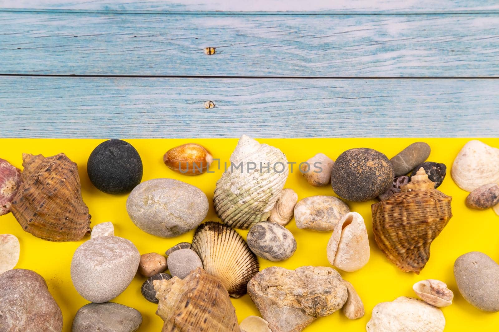 stones and shells on a blue wooden background and a yellow background.Marine theme.