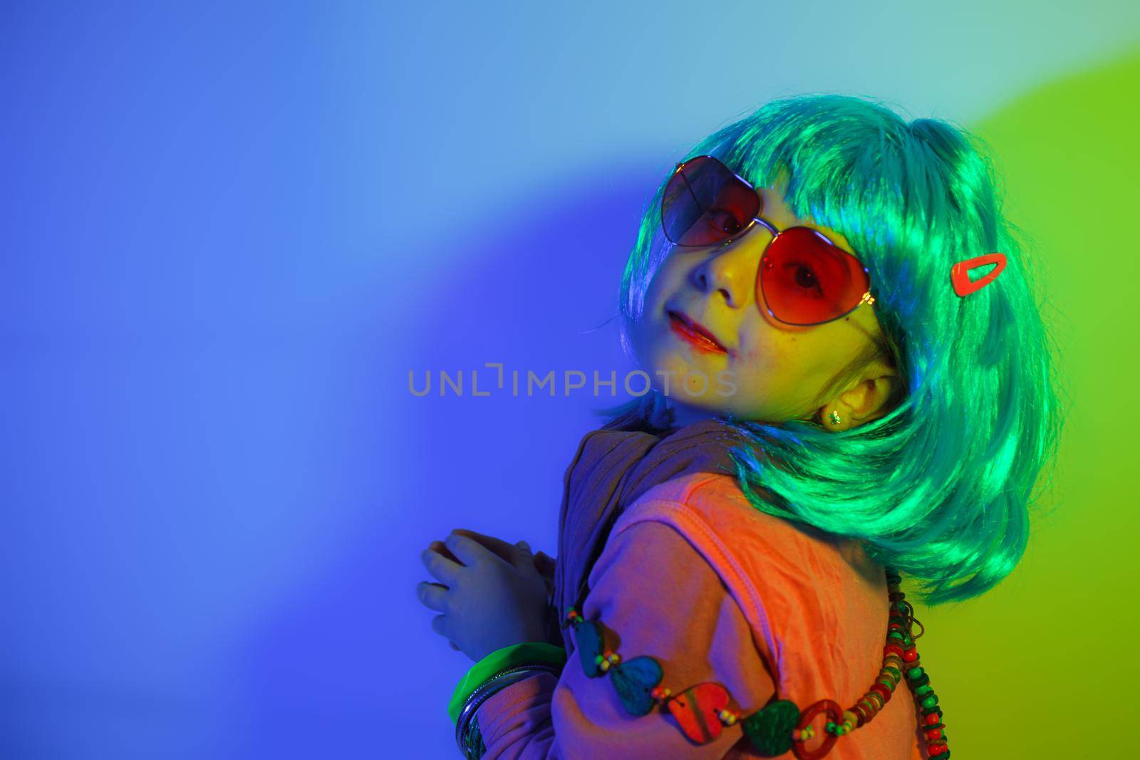 A glamour little girl posing for a photo portrait while wearing a colorful wig on colorful background