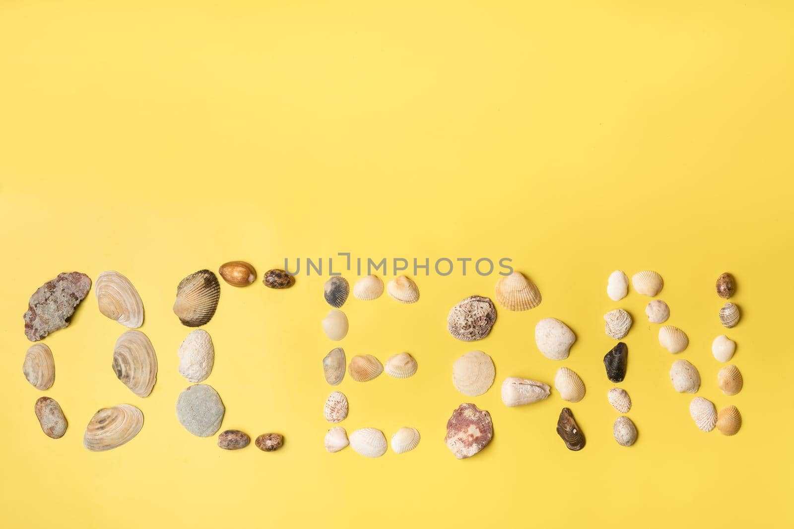 The inscription of the word ocean made of shells on a yellow background.Travel concept.