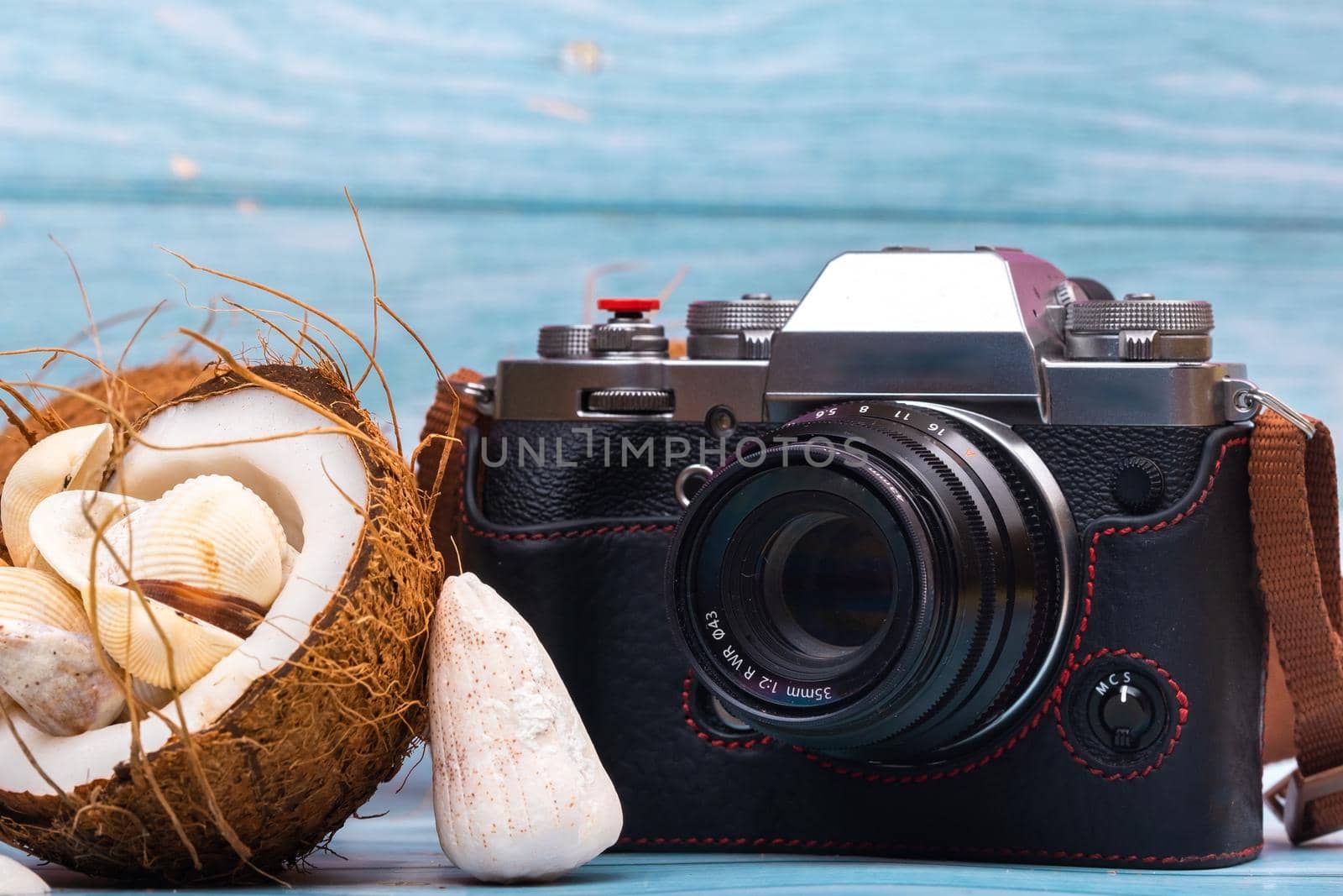 camera,coconuts and shells on a blue wooden background.Marine theme.