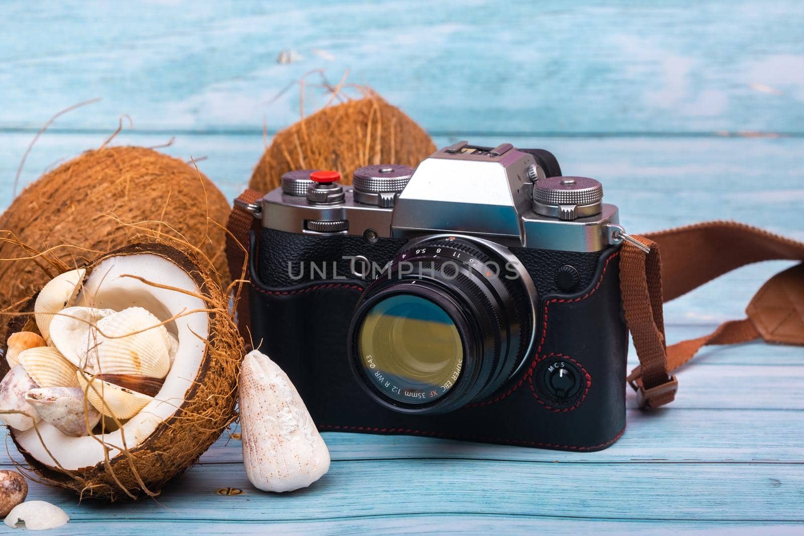 camera,coconuts and shells on a blue wooden background.Marine theme.