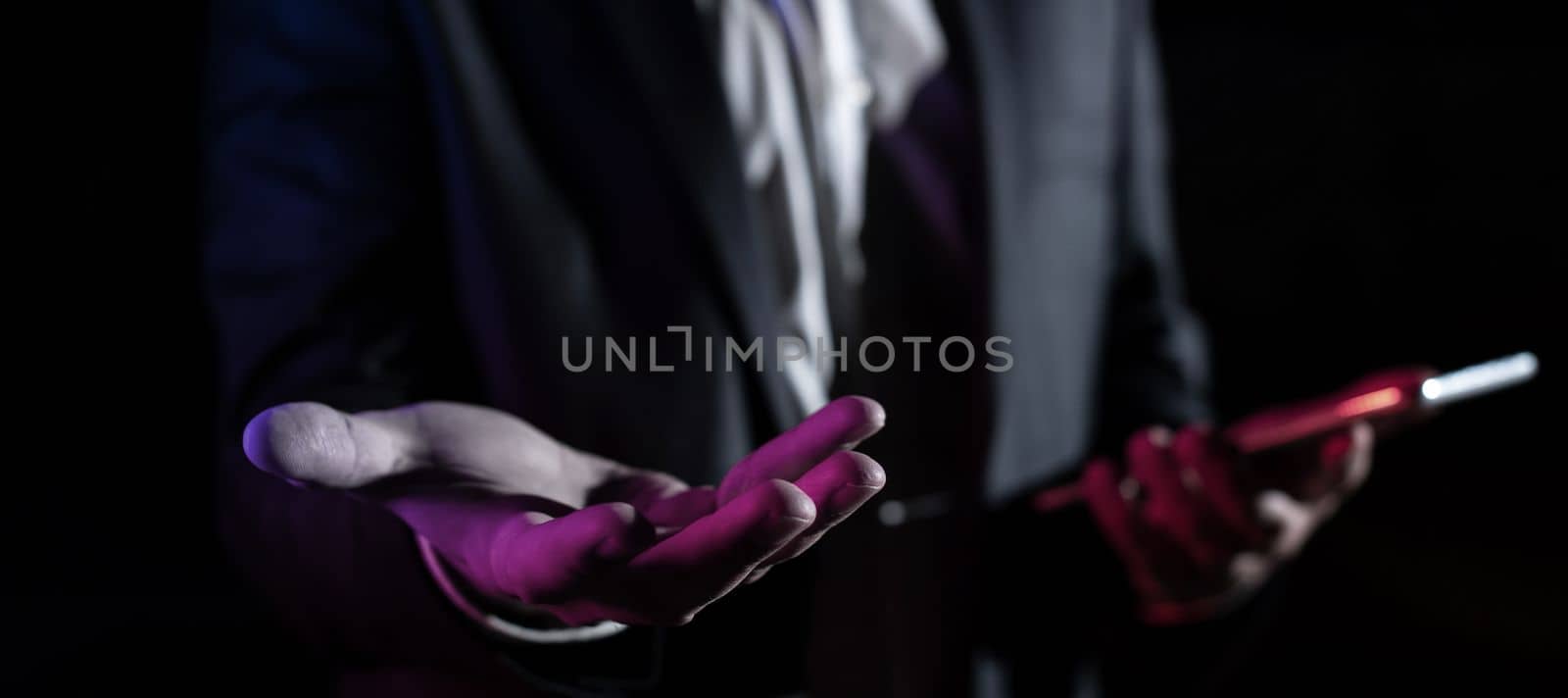 Man Holding Mobile Phone and Holding On Recent Updates With One Hand. Businessman Having Virtual Reality Eyeglasses, Cellphone And Presenting New Idea. by nialowwa