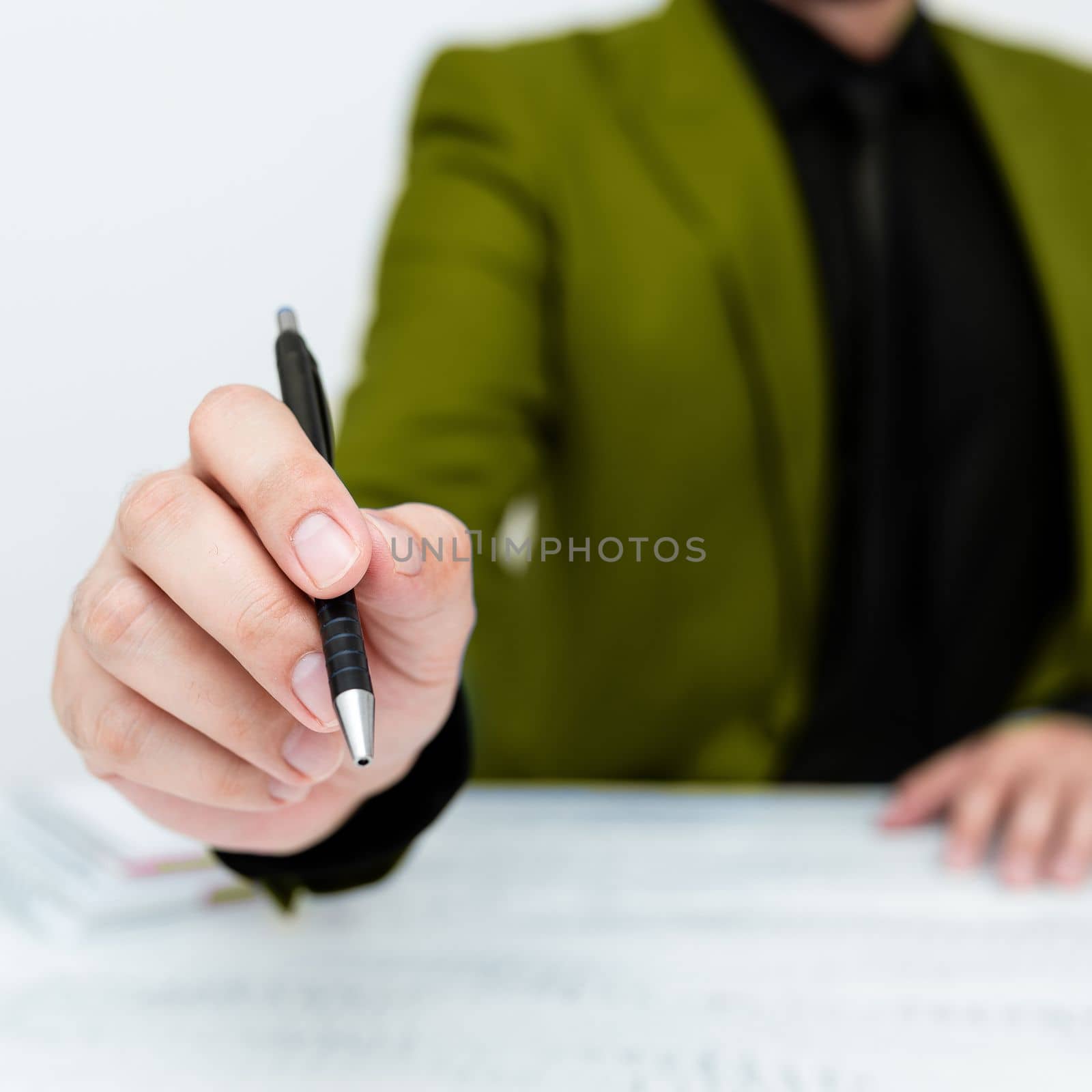 Male mode sitting at table And Pointing With Pen On Important Message.
