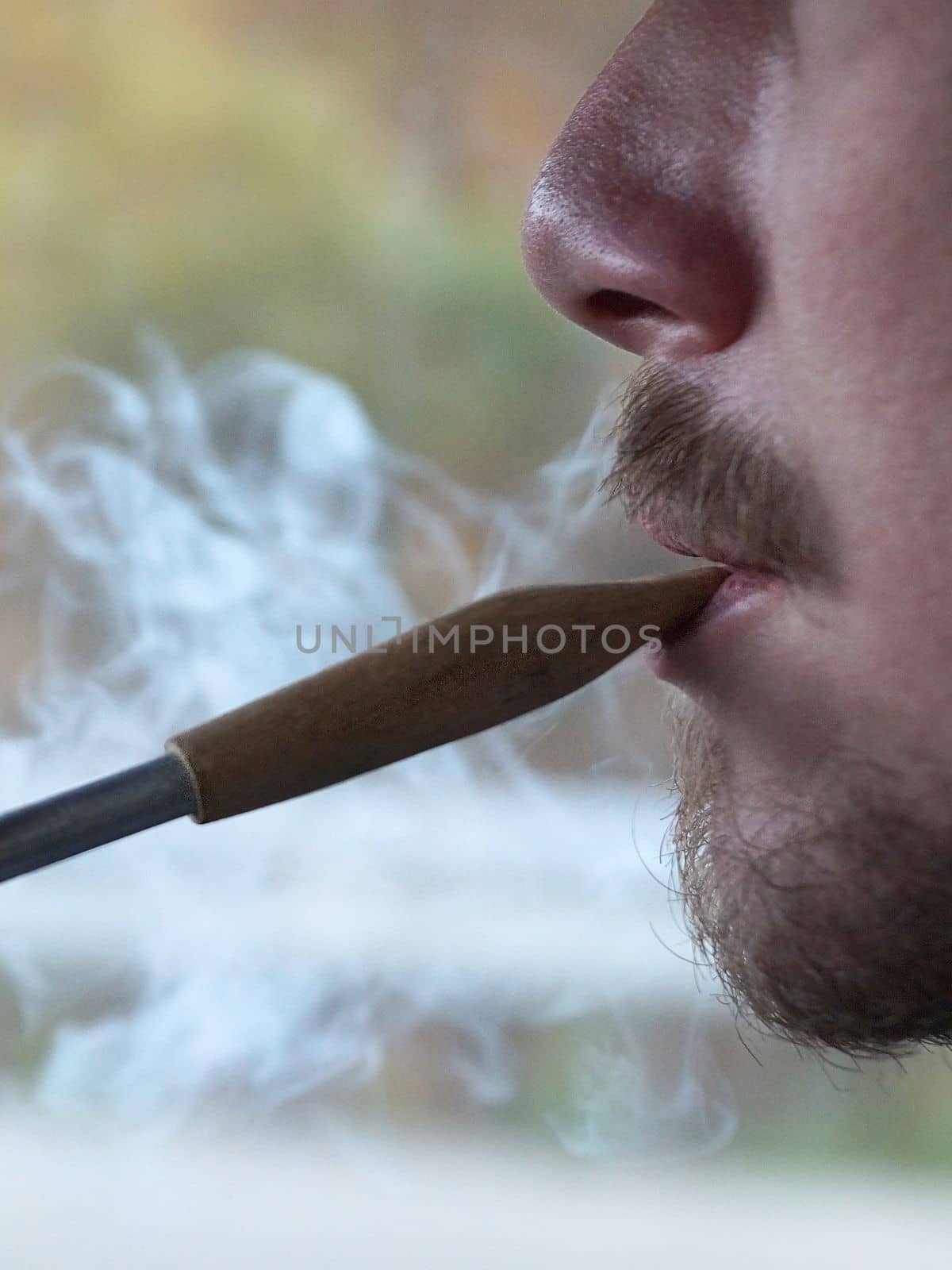 young man smoking a pipe, close-up side view by Annado