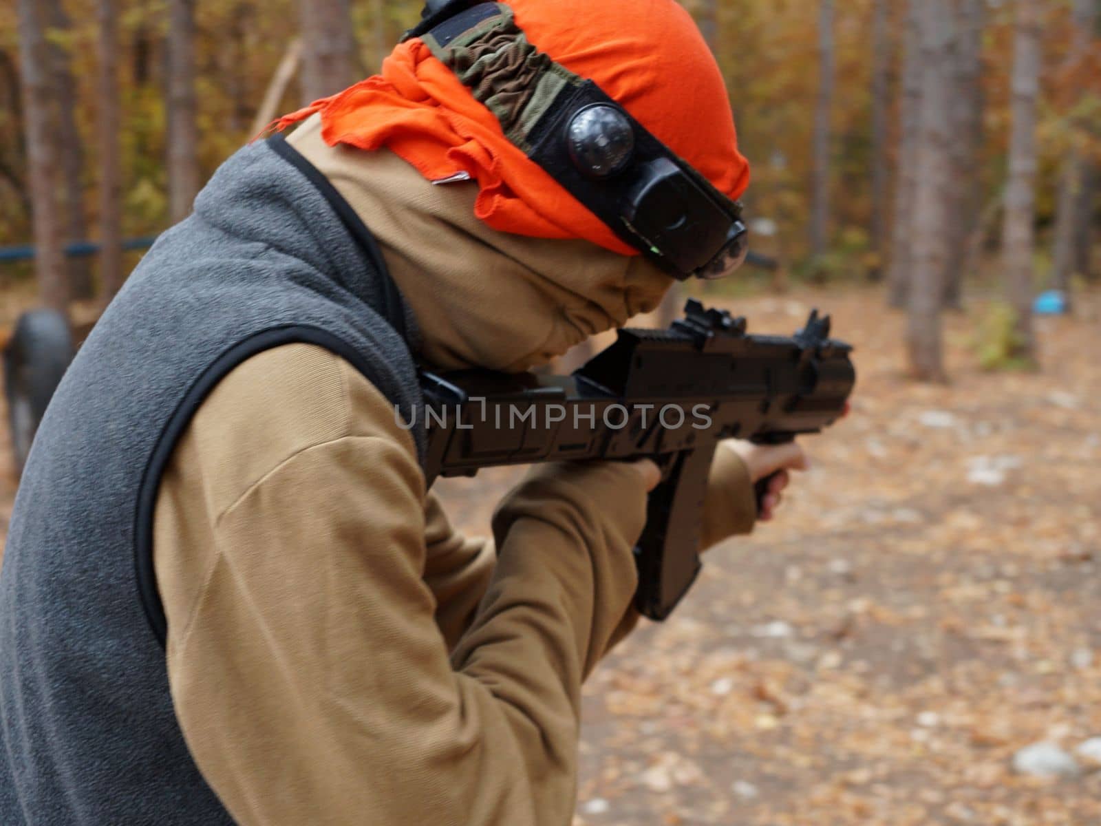 a teenager aiming aim at a laser gun while playing in the forest, rear view.