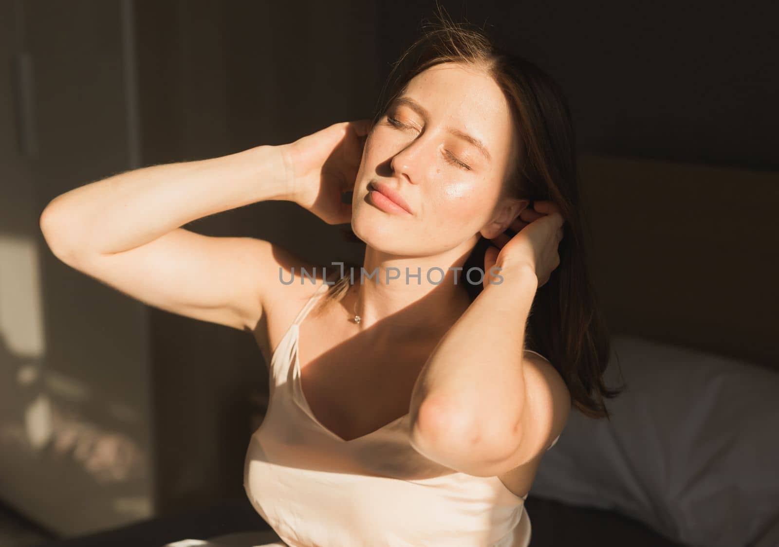 Portrait woman waking up in her bed, she is smiling and stretching. Happy young woman greets new sunny day by Satura86