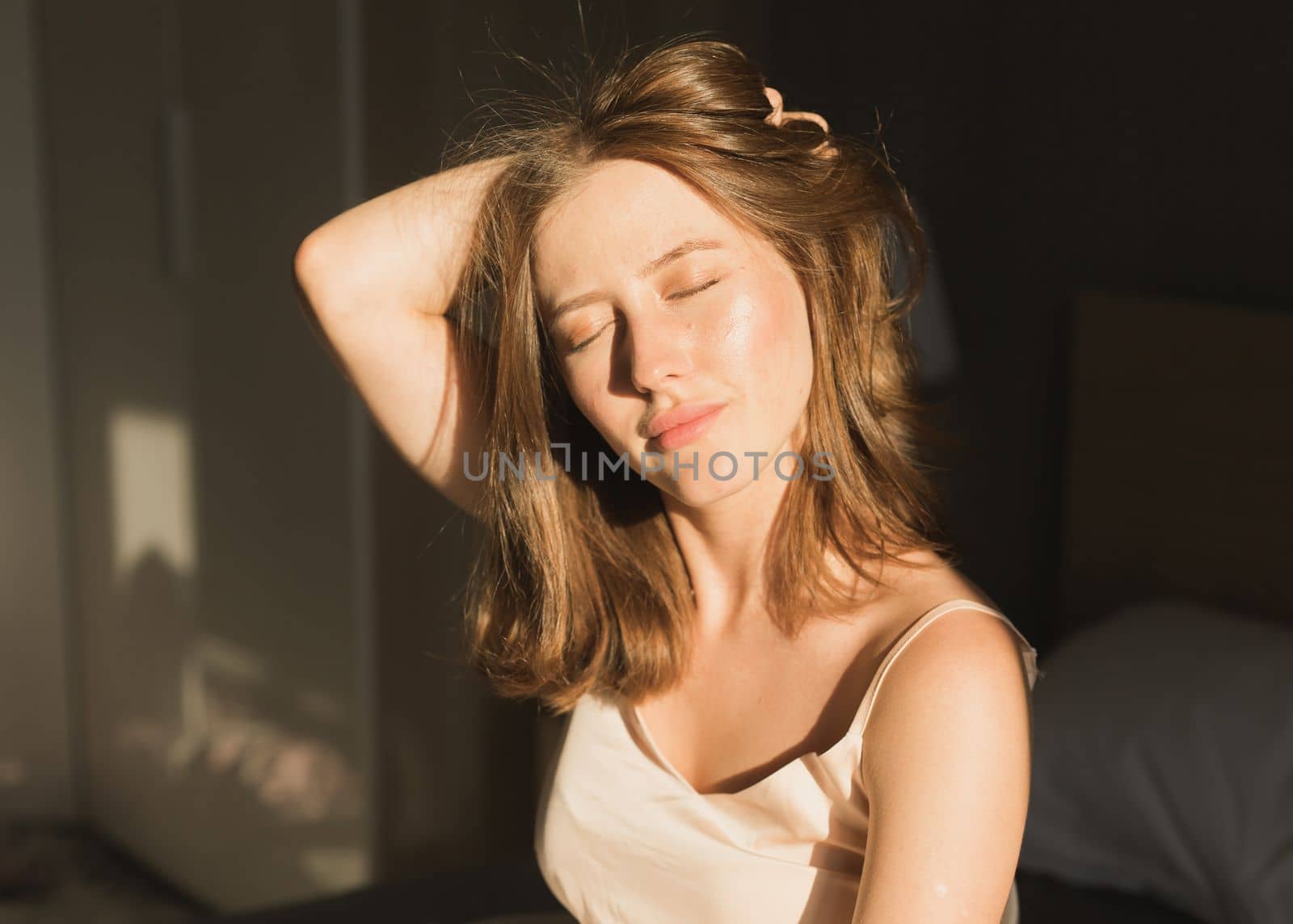 Portrait woman waking up in her bed, she is smiling and stretching. Happy young woman greets new sunny day by Satura86