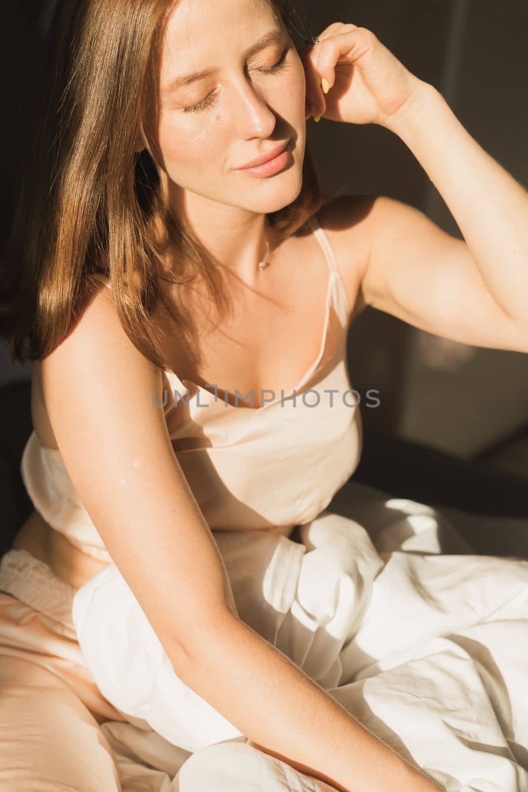 Portrait woman waking up in her bed, she is smiling and stretching. Happy young woman greets new sunny day by Satura86