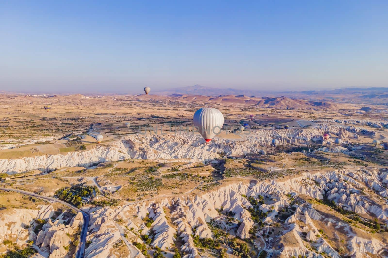 Colorful hot air balloons flying over at fairy chimneys valley in Nevsehir, Goreme, Cappadocia Turkey. Spectacular panoramic drone view of the underground city and ballooning tourism. High quality by galitskaya