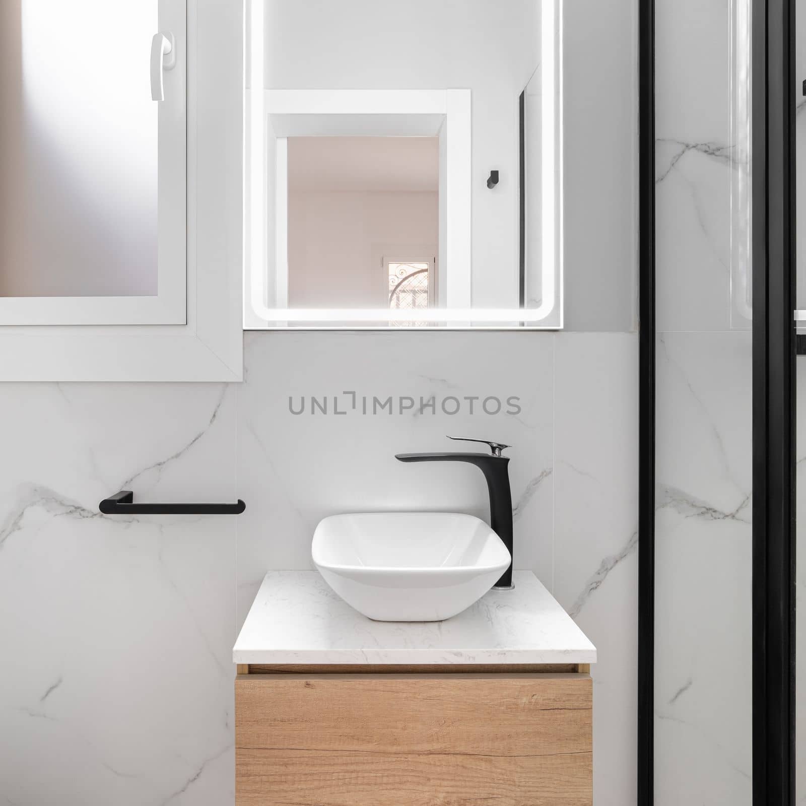 Bright bathroom boasts a sleek and minimalist style, featuring a gleaming white sink set against a stunning black framed mirror, creating a modern and sophisticated look. by apavlin