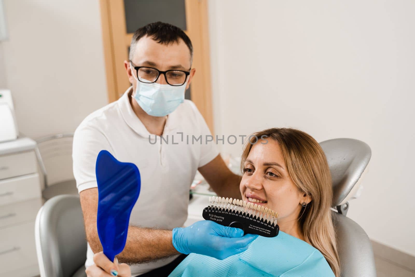 Teeth whitening. Patient looking at teeth color shades guide. Dentistry. Doctor checking tooth color matching samples in dental clinic