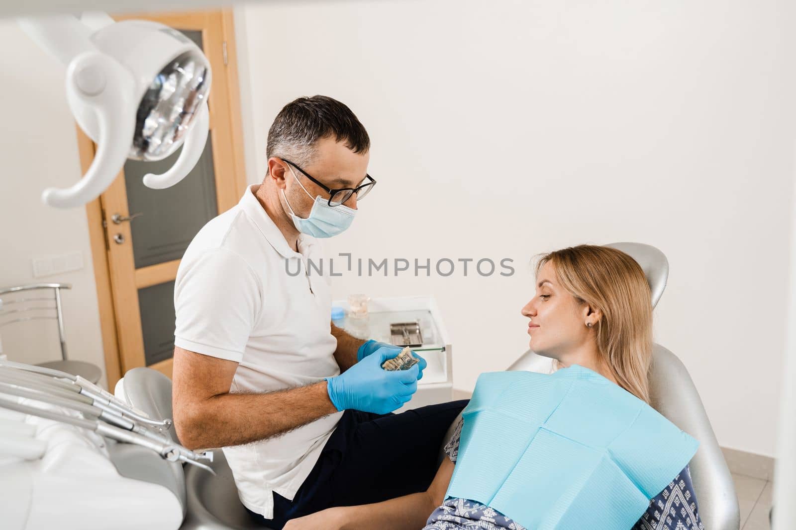 Dental prosthetics and implants. Doctor dentist shows artificial plastic jaw with dental implants. Dental prosthetics consultation with dentist for patient woman in dentistry. by Rabizo