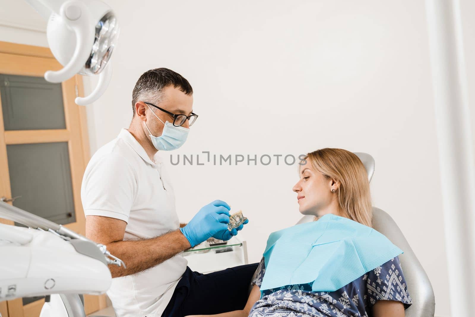 Dental prosthetics and implants. Doctor dentist shows artificial plastic jaw with dental implants. Dental prosthetics consultation with dentist for patient woman in dentistry. by Rabizo