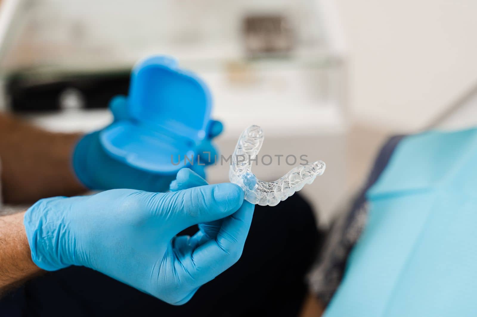 Clear aligner for bite correction and shape of teeth close-up. Orthodontist shows transparent removable retainer for patient woman in dentistry