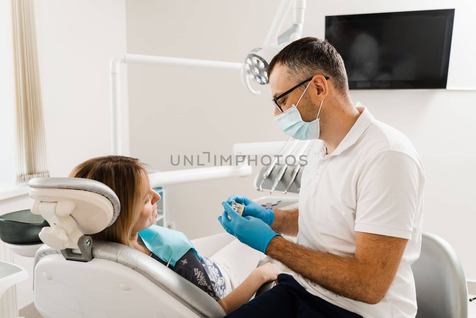 Dental prosthetics and implants. Doctor dentist shows artificial plastic jaw with dental implants. Dental prosthetics consultation with dentist for patient woman in dentistry