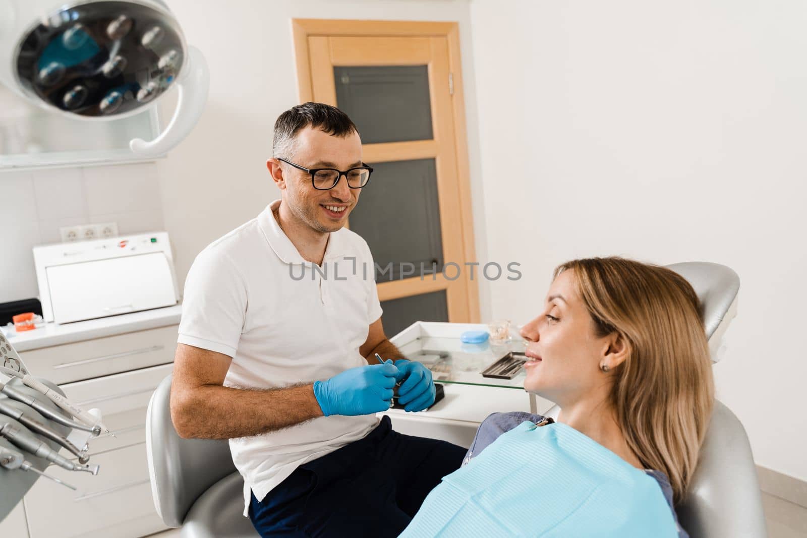 Happy woman patient of dentistry. Teeth treatment. Attractive girl sitting in dental office and smiling. Dentist visiting and consultation