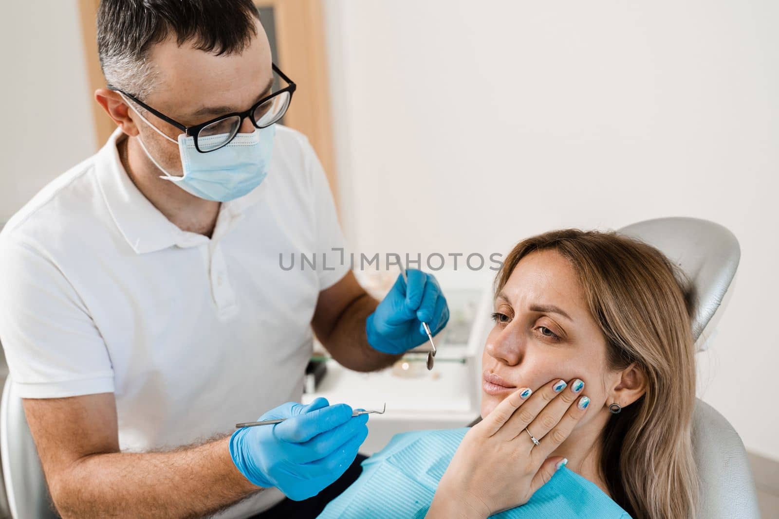 Dentist examines woman with toothache at consultation and treatment at the dentist in dentistry. Dentist treats caries teeth for girl. by Rabizo