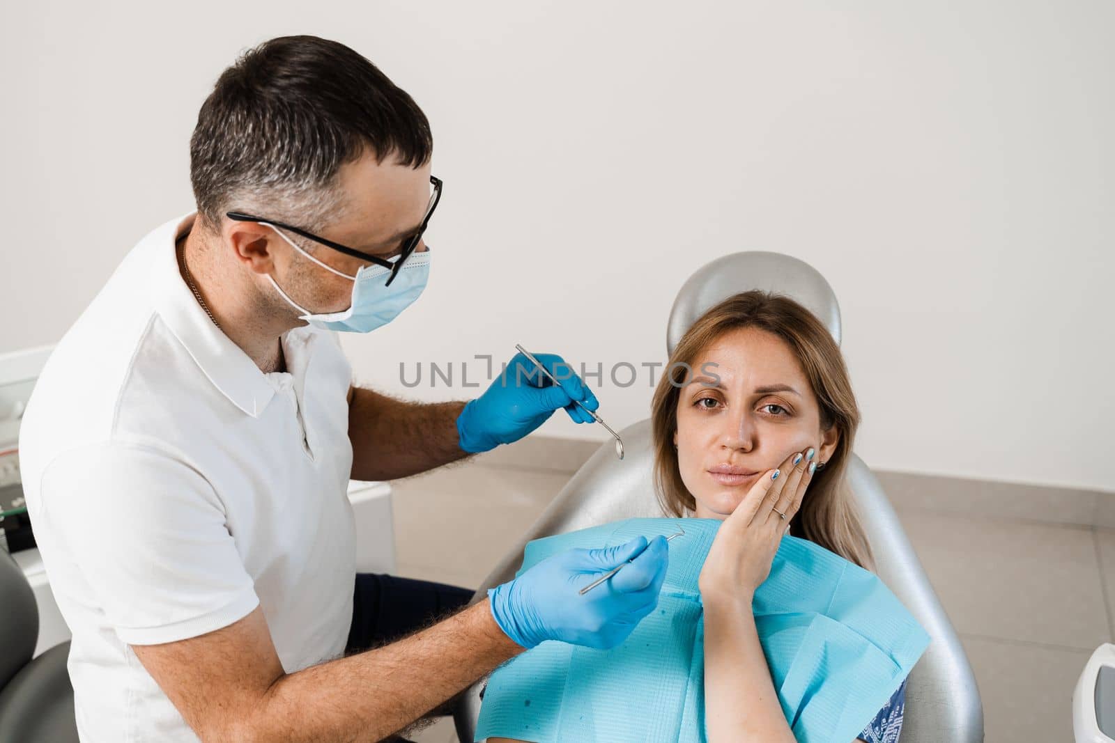 Dentist examines woman with toothache at consultation and treatment at the dentist in dentistry. Dentist treats caries teeth for girl. by Rabizo