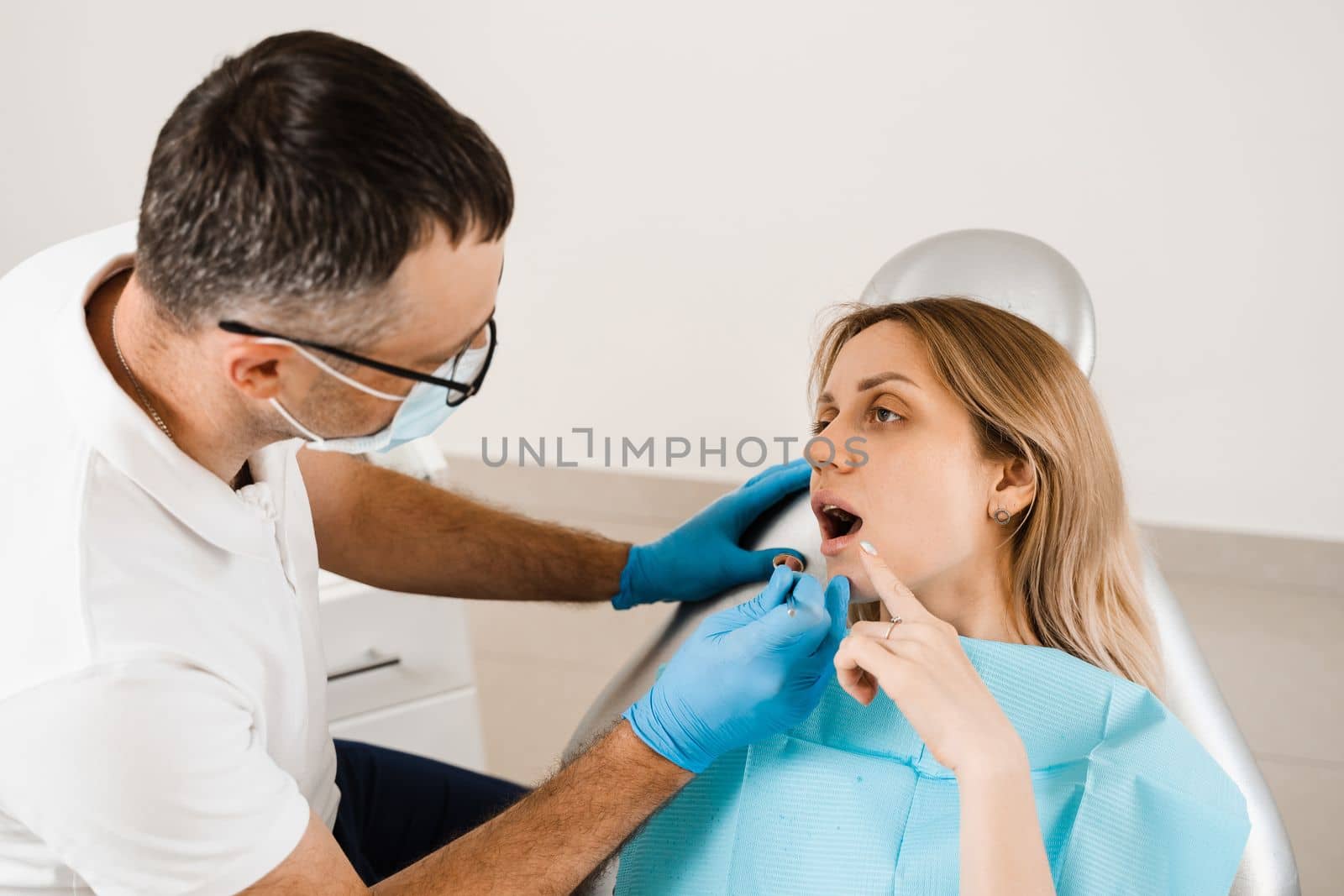 Attractive woman afraid of dentist. Dentist consults frightened girl in dentistry. Treatment of teeth and toothache in dentistry