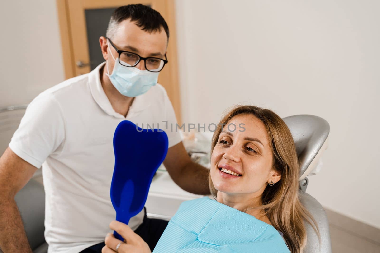 Consultation with dentist at dentistry. Teeth treatment. Woman looking in the mirror at the dentist. Happy girl patient of dentistry. by Rabizo