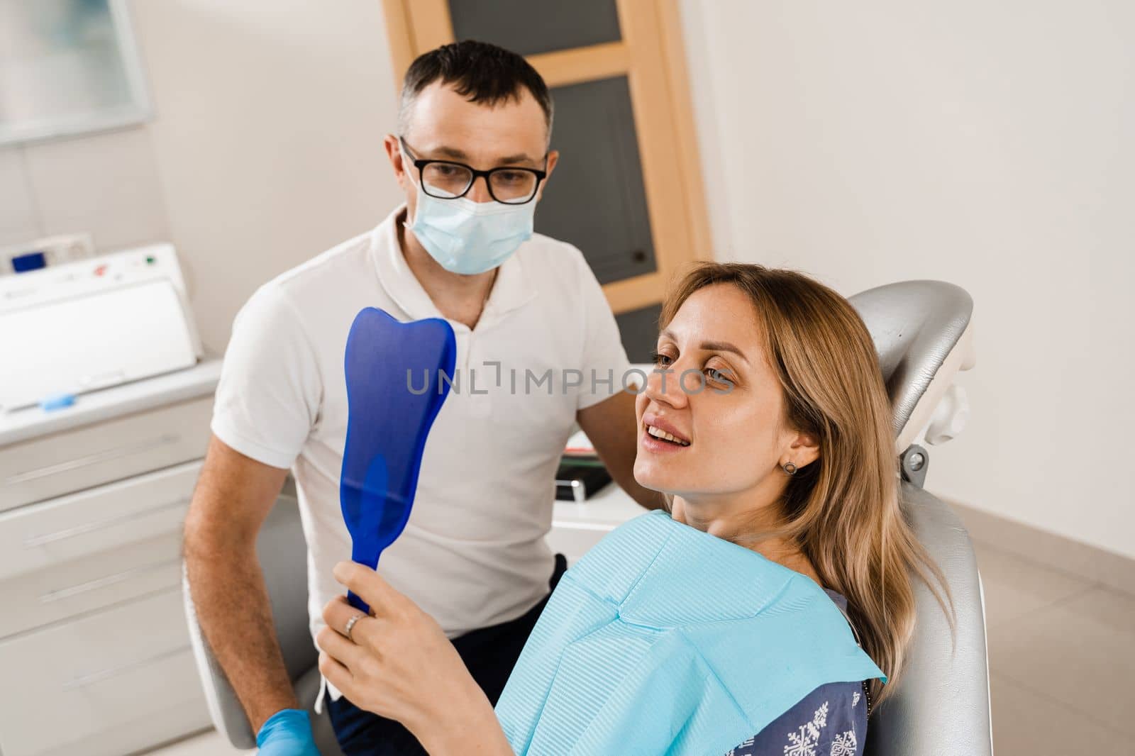 Consultation with dentist at dentistry. Teeth treatment. Woman looking in the mirror at the dentist. Happy girl patient of dentistry. by Rabizo