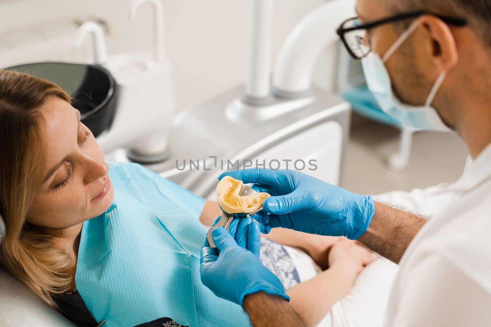 Dentist showing cast of teeth of patient woman before dental implantation. Procedure of creating dental prostheses, crowns and aligners