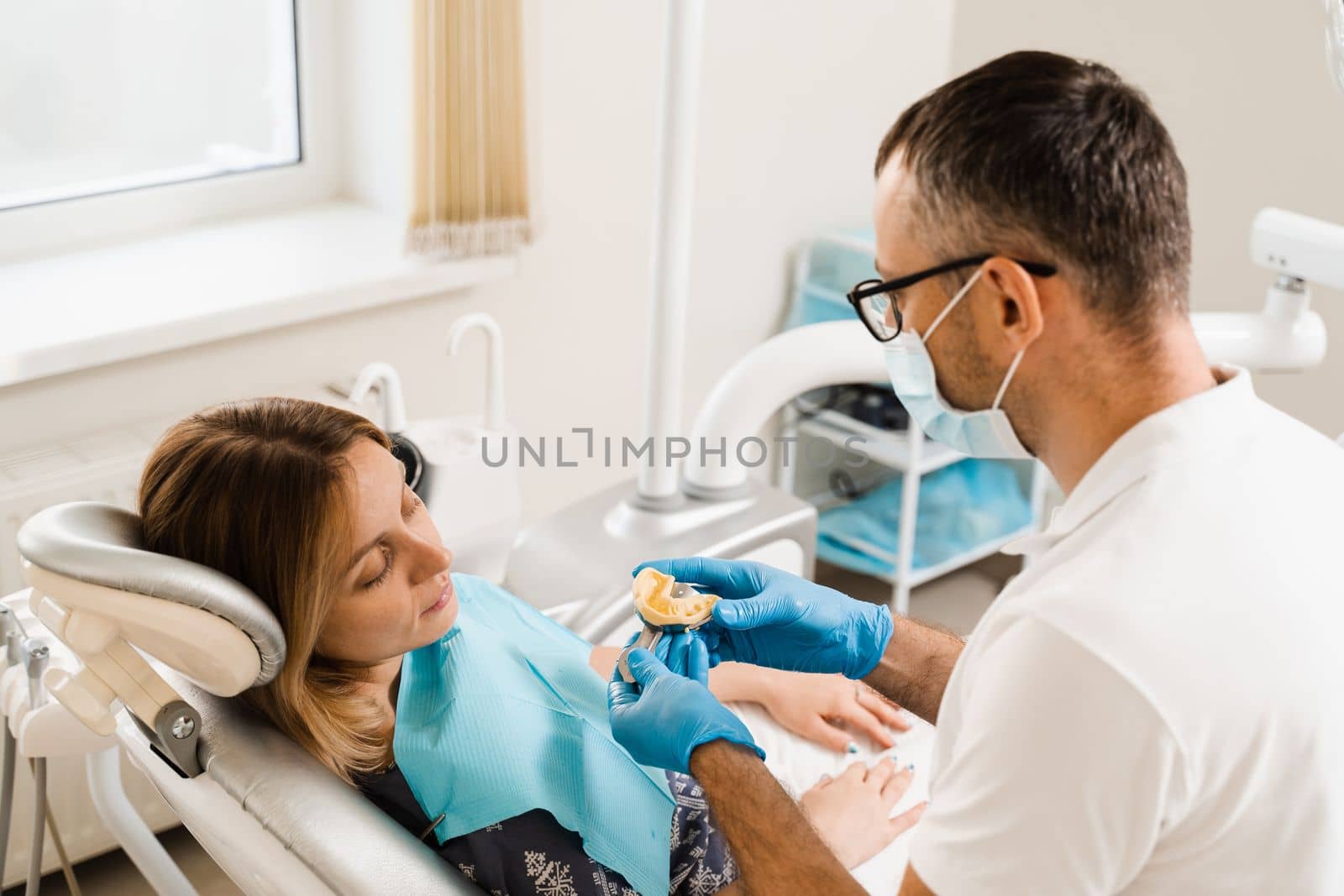 Dentist showing cast of teeth of patient woman before dental implantation. Procedure of creating dental prostheses, crowns and aligners