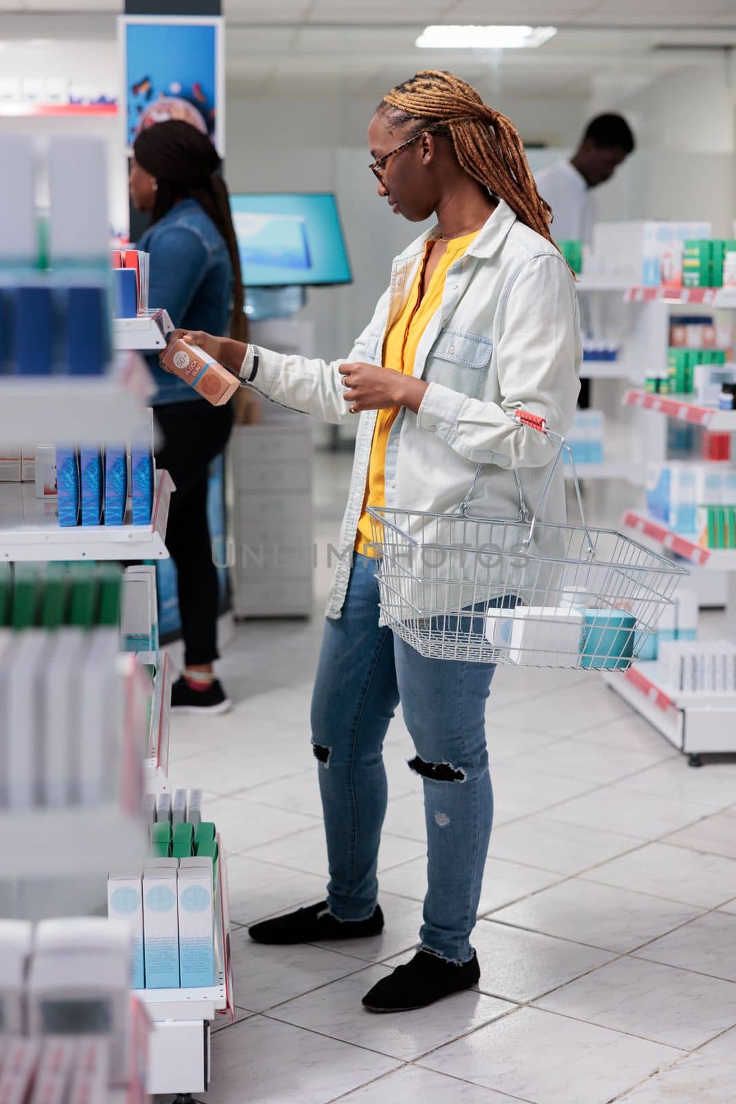 African american buyer choosing sunscreen in drugstore shelf by DCStudio