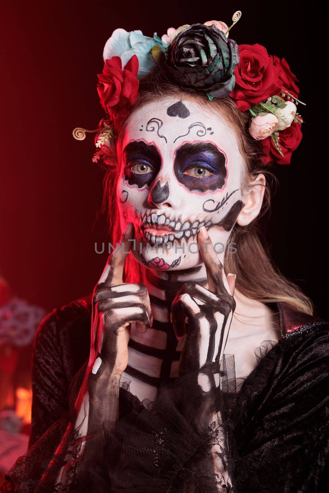 Spooky lady of death doing flirty kissy face on camera, wearing flowers crown and skull make up. Looking like la cavalera catrina or santa muerte, being charming and romantic on dios de los muertos.